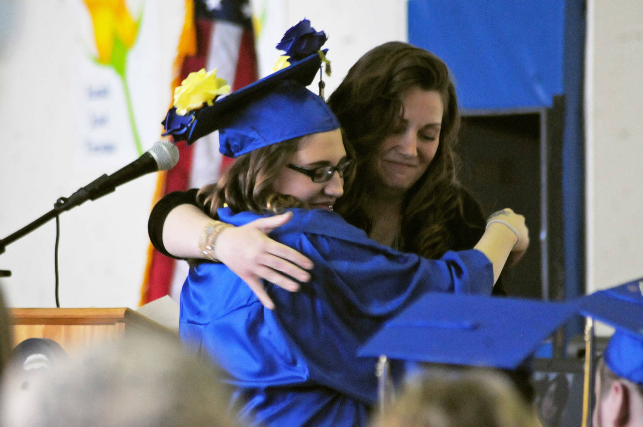 Kenai Alternative High School graduate Larissa Pittman hugs school secretary Jacquelynn Tomrdle at the high school’s graduation ceremony on Tuesday, May 22, 2018 in Kenai, Alaska. Kenai Alternative High School provides more flexible edcuation for students who struggled in traditional high school environments, scheduling classes around jobs, children and life circumstances to help students achieve their high school diplomas. (Photo by Elizabeth Earl/Peninsula Clarion)