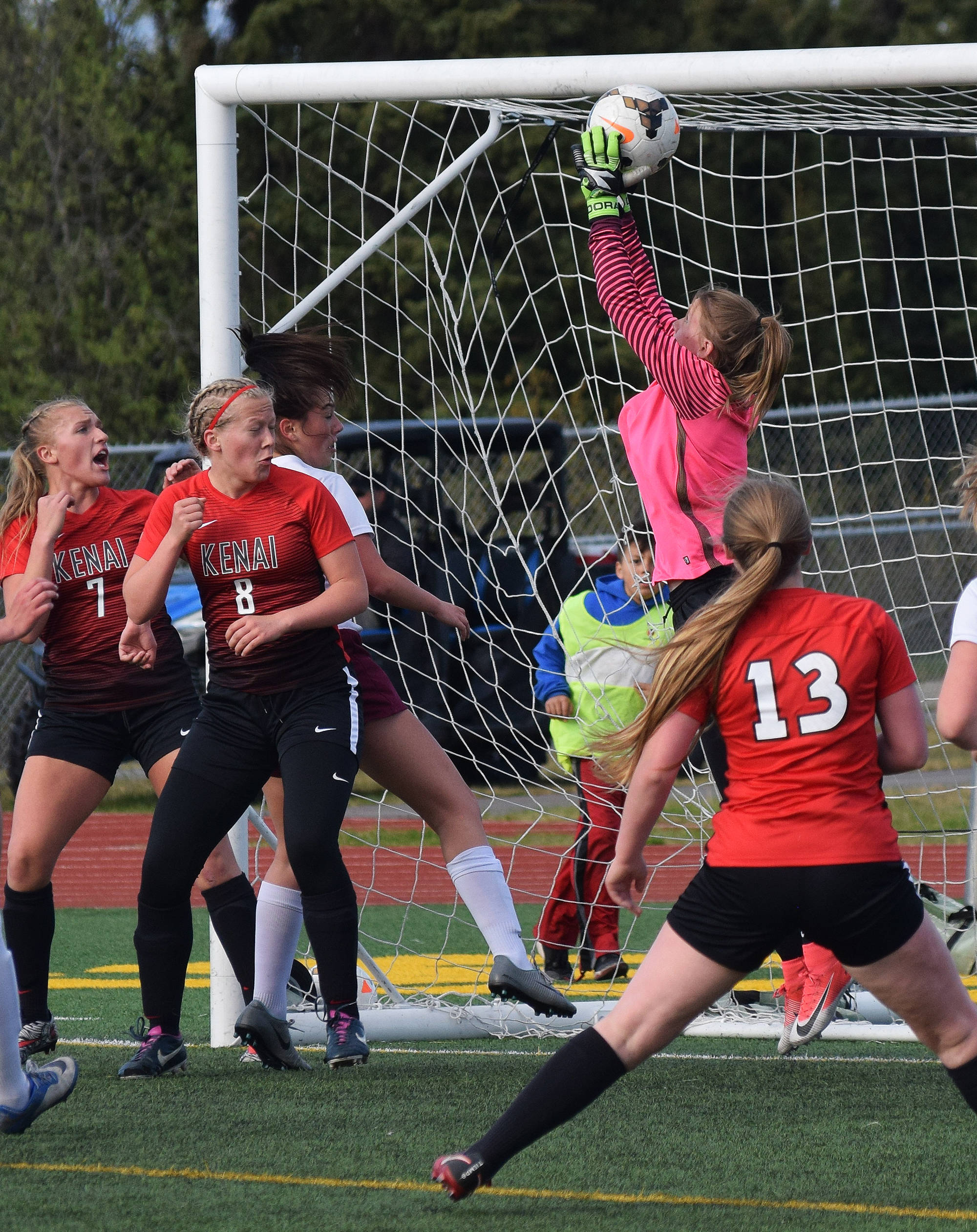 Kenai Central goalkeeper Kailey Hamilton (in pink) leaps to save a shot from Grace Christian Thursday in the Division II state soccer tournament at Service High School. (Photo by Joey Klecka/Peninsula Clarion)