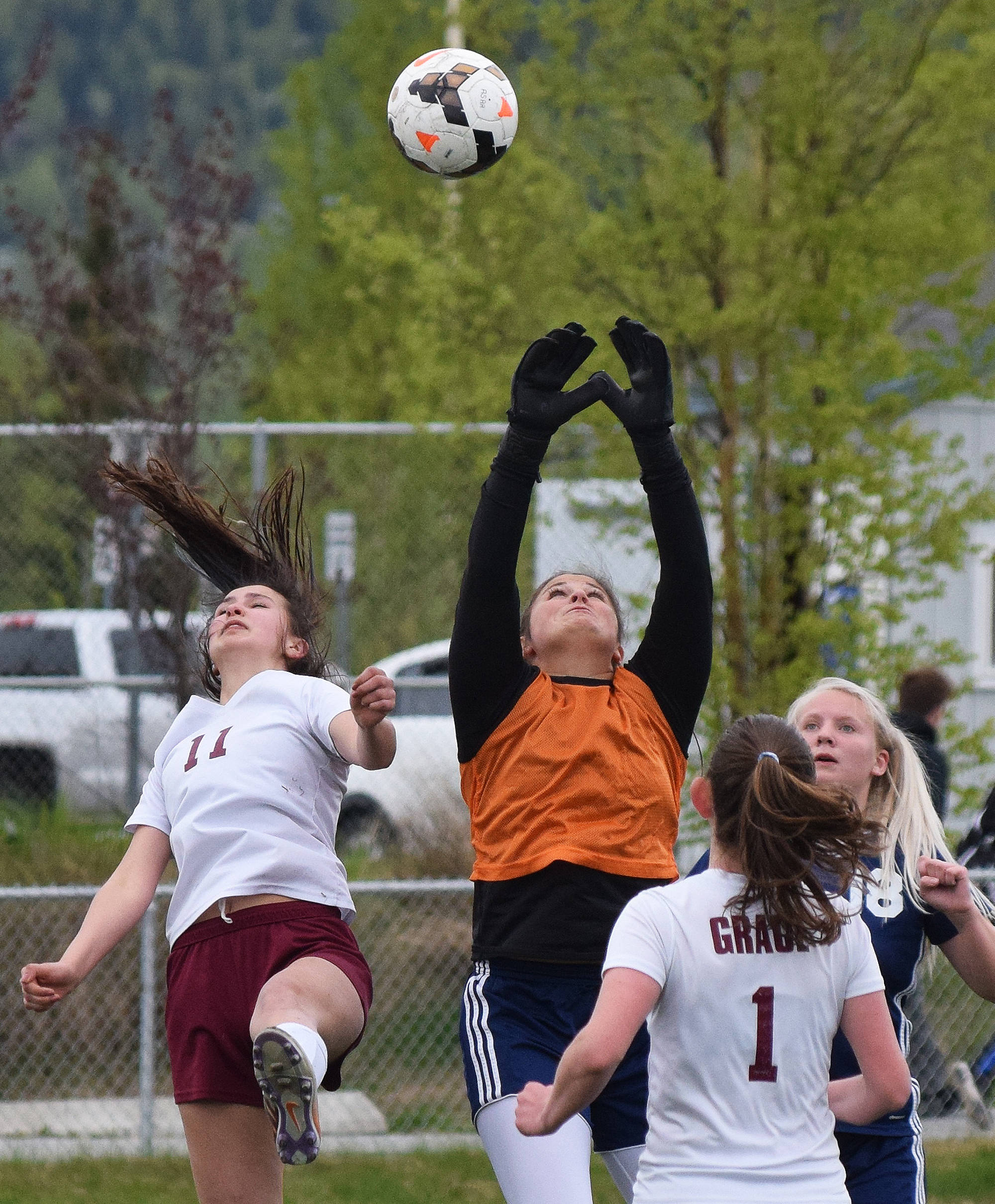 Soldotna goalkeeper Maddie Kindred (in orange) reaches high to make a save Friday in a Division II state tournament semifinal against Grace Christian at Service High School. (Photo by Joey Klecka/Peninsula Clarion)