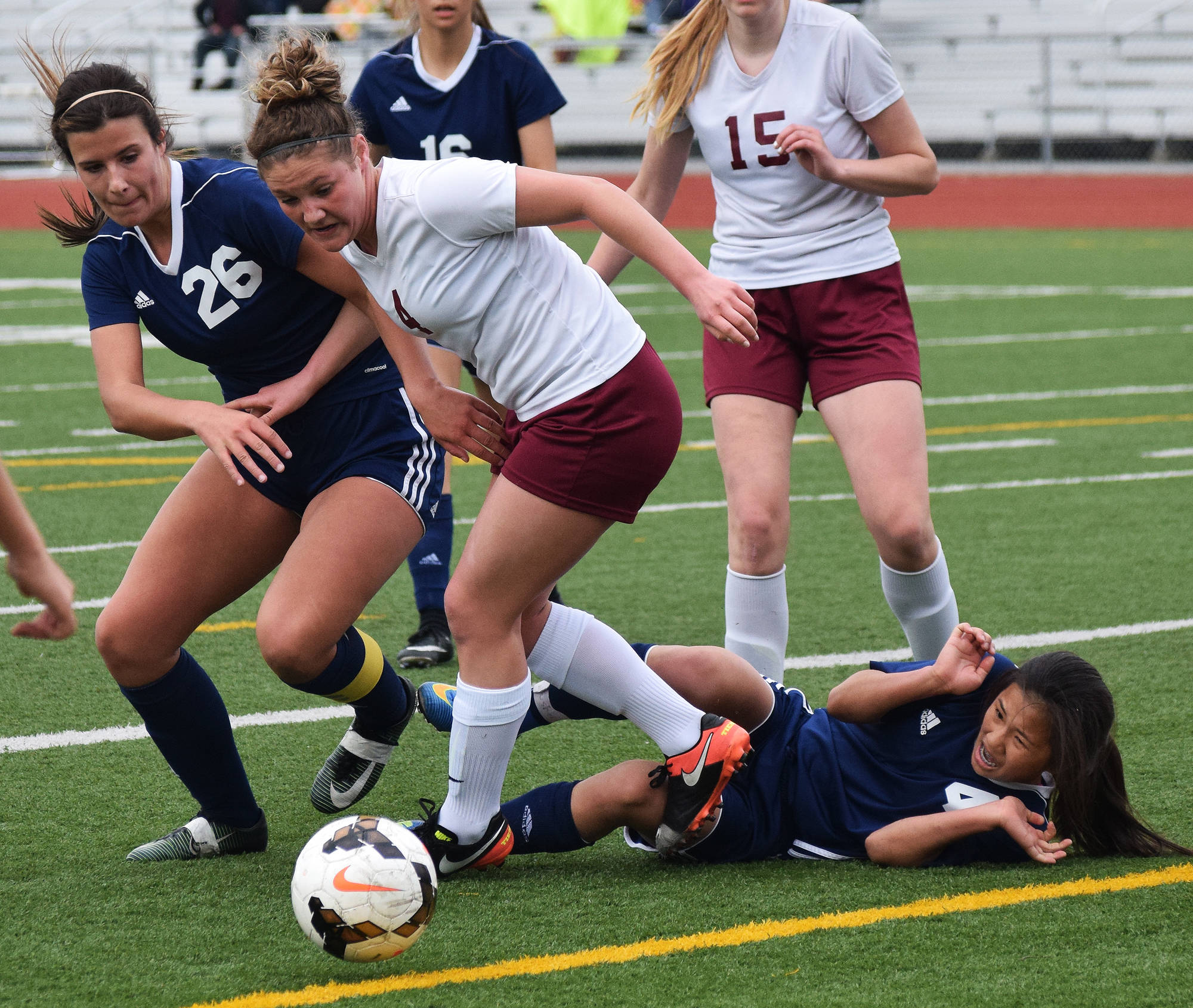 Soldotna’s Meijan Leaf (on ground) protects herself from an aggressive attack by Grace Christian’s Maddy Morgan and Soldotna’s Whitney Wortham (26) Friday in a Division II state tournament semifinal at Service High School. (Photo by Joey Klecka/Peninsula Clarion)