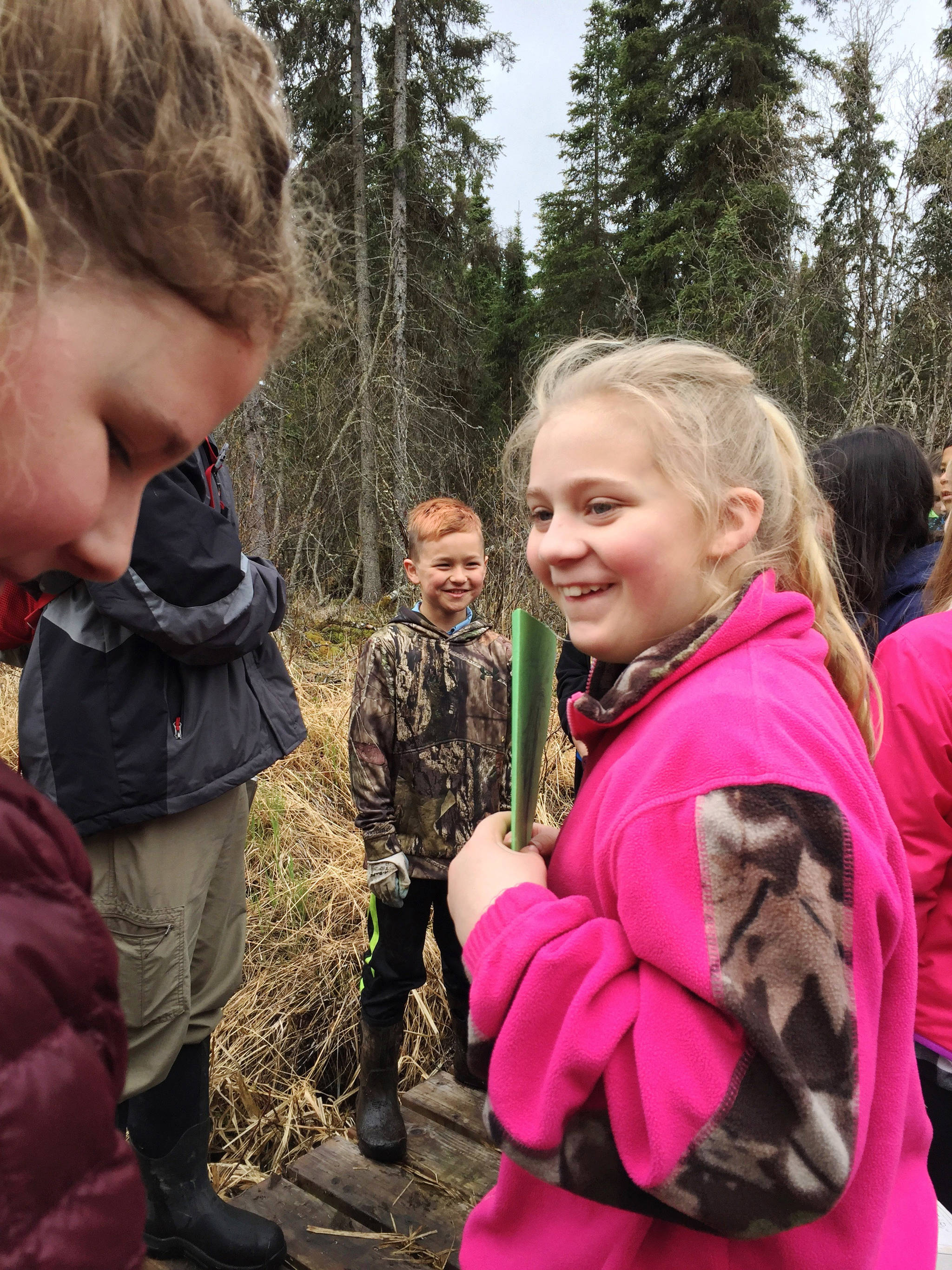 Kalifornsky Beach Elementary School fifth grade students Kennedy Whitney (left), Marshal Burnett (center) and Alyssa McDonald (center) work together to distribute plant identification signs they made on a trail near the school on Friday, May 18, 2018 near Soldotna, Alaska. The class worked with the Kenai Watershed Forum this year to improve the trail and place plant identification signs along it. (Photo by Elizabeth Earl/Peninsula Clarion)