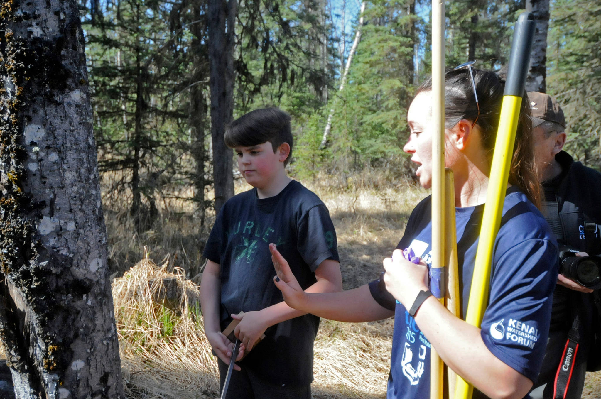 Jordan Hinz (left) askso for advice from Jen Hester (right) of the Kenai Watershed Forum to identify a black cottonwood tree on a trail near the school on Tuesday, May 22, 2018 in Kasilof, Alaska. (Photo by Elizabeth Earl/Peninsula Clarion)