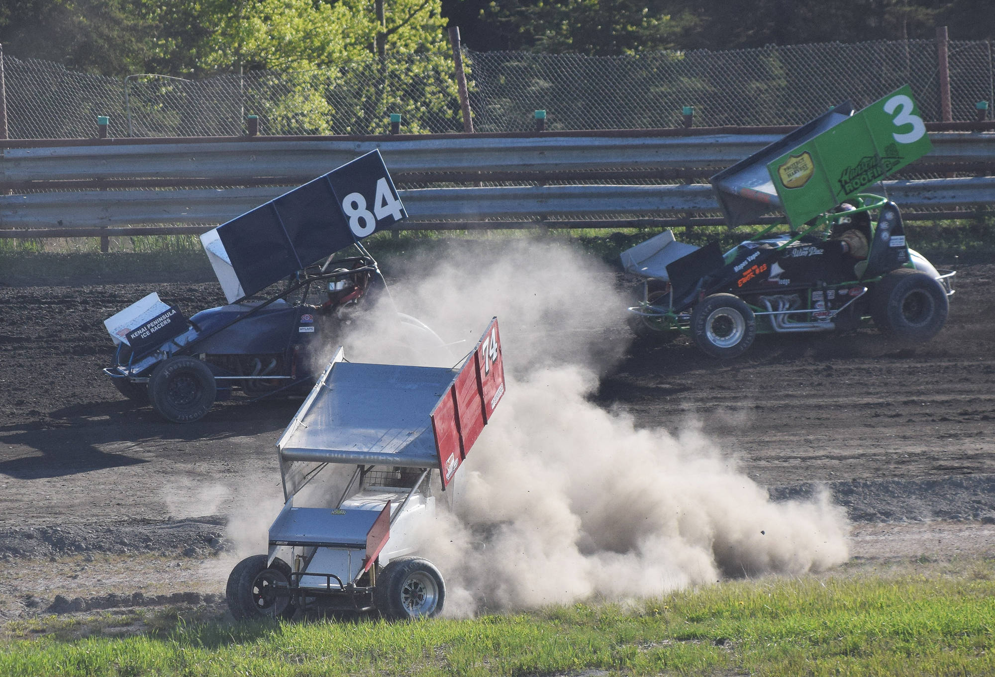 Elton McGahan goes off road in his sprint car as fellow racers Jimmie Hale (84) and Geoff Clark (3) make their way by Saturday night at Twin City Raceway in Kenai. (Photo by Joey Klecka/Peninsula Clarion)