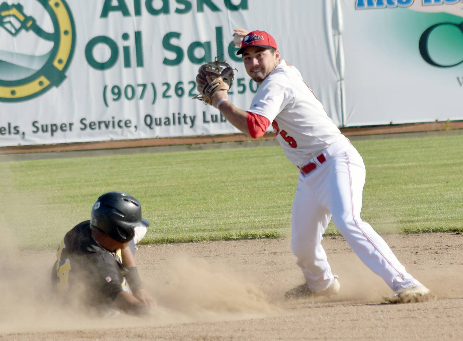 Oilers shortstop Paul Kunst forces out JC Correa of the Anchorage Bucs but throws late to first for the double play Thursday, June 7, 2018, at Coral Seymour Memorial Park in Kenai. (Photo by Jeff Helminiak/Peninsula Clarion)