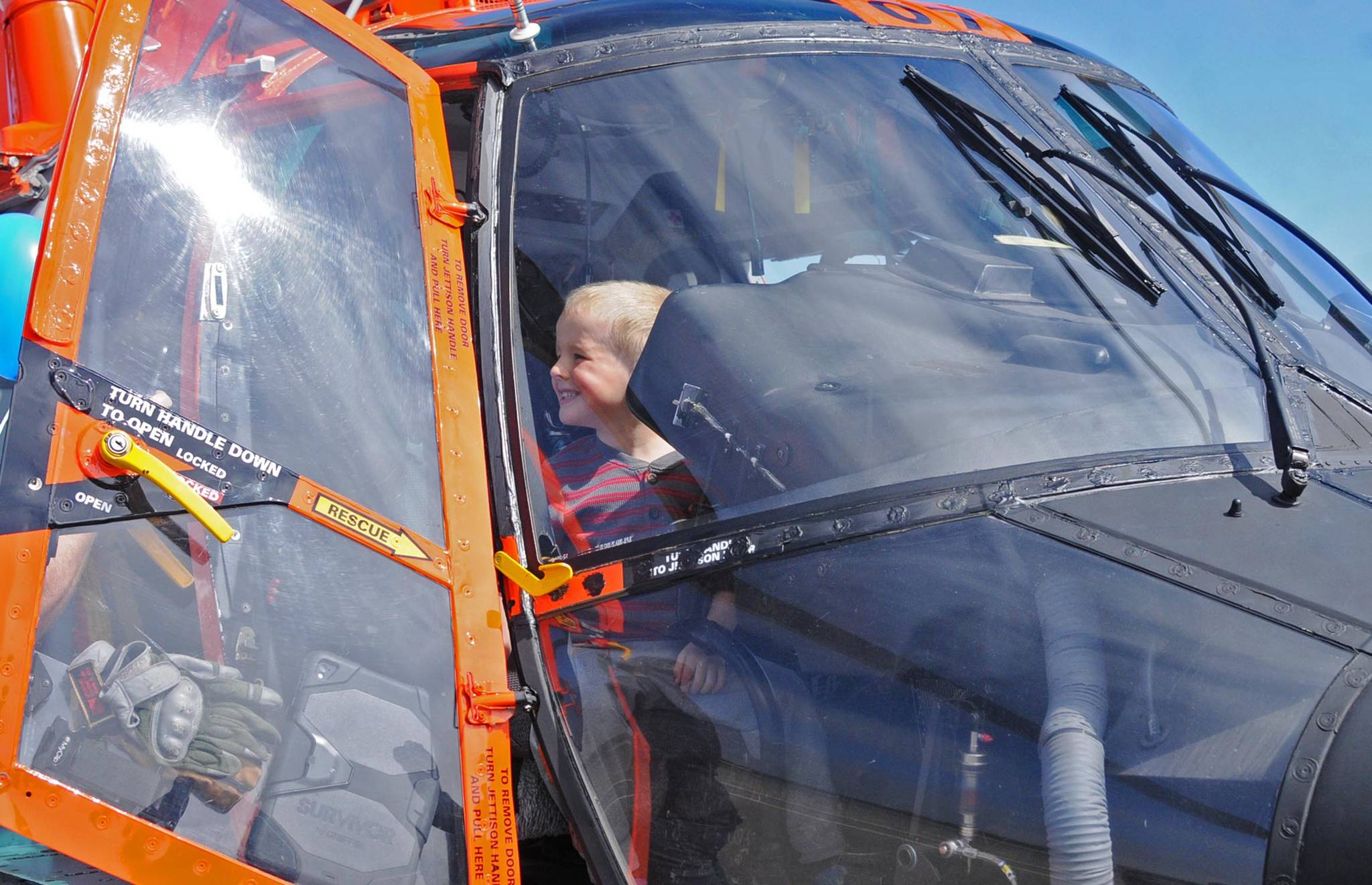 Erik Hamilton, 3 1/2, enjoys the view from the cockpit of a U.S. Coast Guard helicopter at the Kenai Municipal Airport’s annual Air Fair on Saturday, June 9, 2018 in Kenai, Alaska. The Air Fair opens up the tarmac to the public to come and get a closer look at a wide variety of aircraft, including small civilian planes, a commercial plane owned by Hilcorp and larger military planes. (Photo by Elizabeth Earl/Peninsula Clarion)