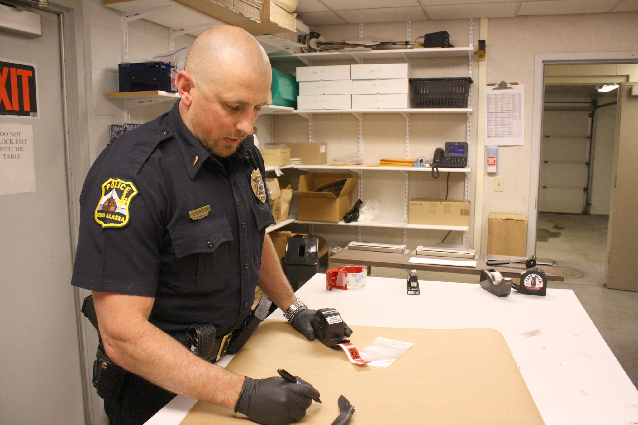 Kenai Police Lt. Ben Langham demonstrates how police prepare evidence for storage on Thursday at Kenai Police Department headquarters on Thursday. (Photo by Erin Thompson/Peninsula Clarion)