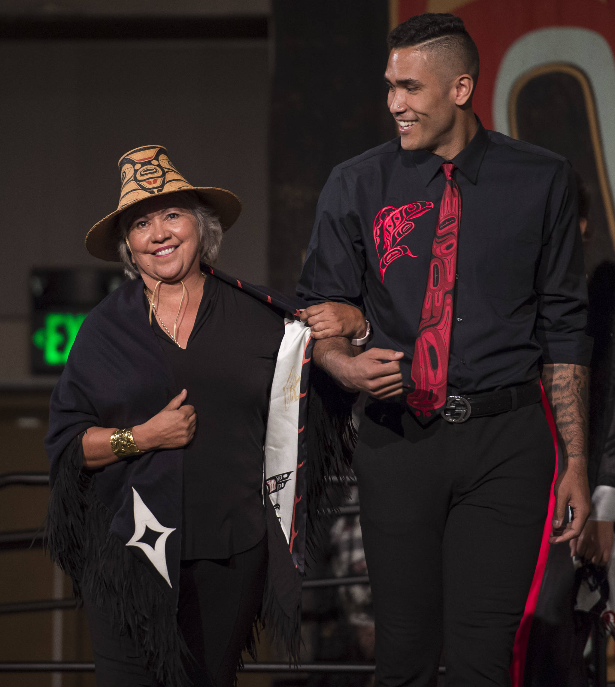 Model Damen Bell-Holter escorts designer Dorothy Grant across the stage at the Native Fashion Show at Centennial Hall on Friday, June 8, 2018. (Michael Penn | Juneau Empire)