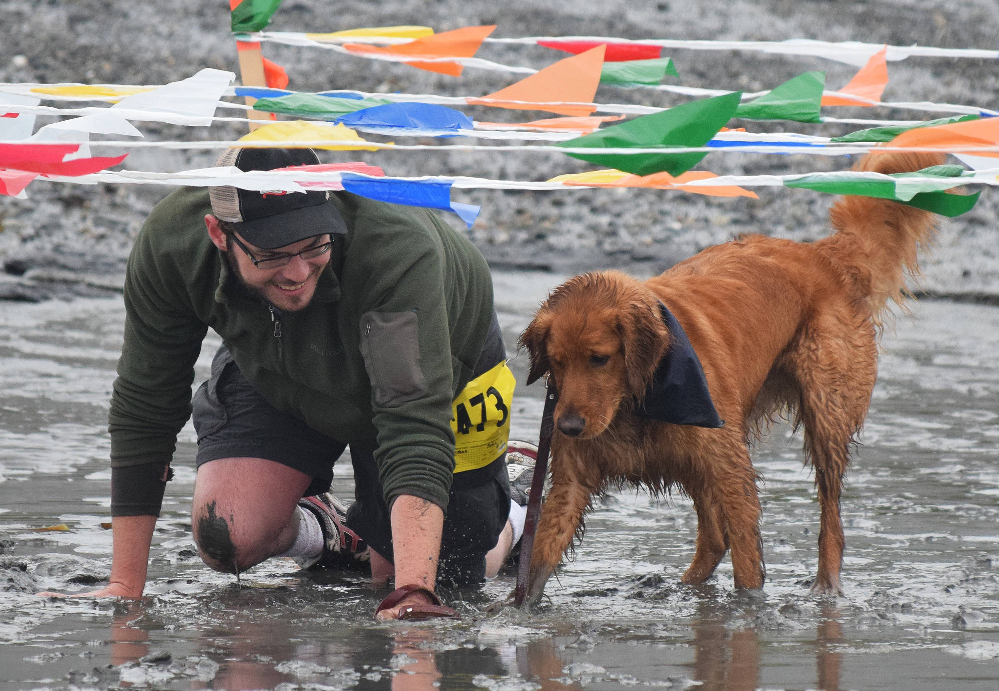 John Sherman crawls through the mud with dog Ranger, Saturday at the fourth annual Clam Scramble 5K in Ninilchik. (Photo by Joey Klecka/Peninsula Clarion)