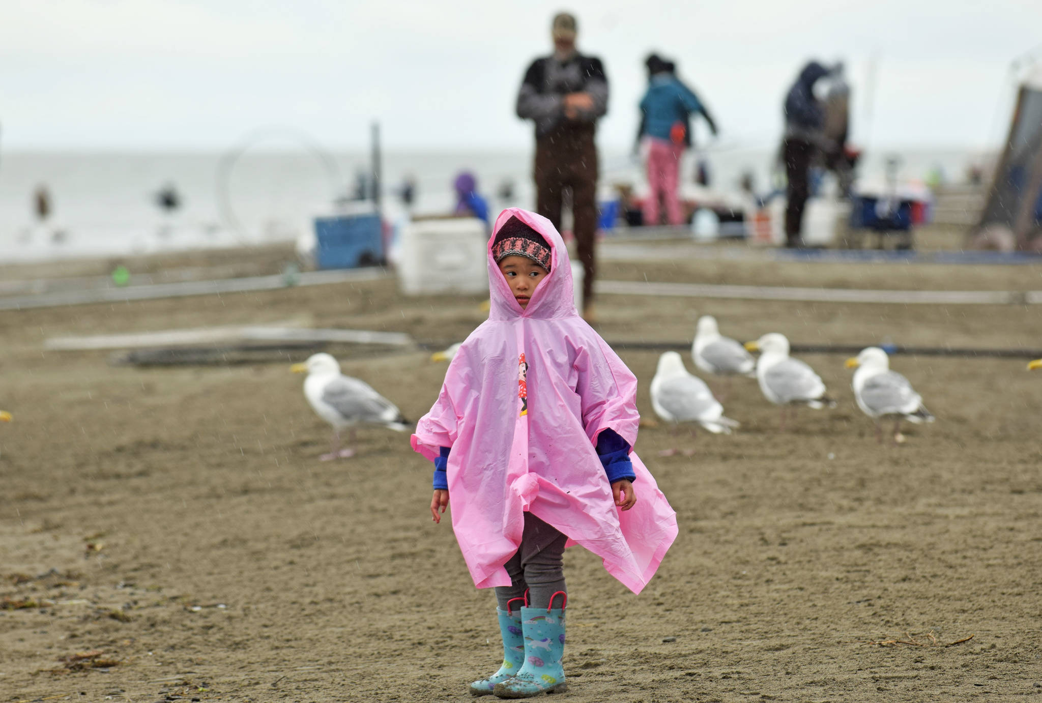 A young girl takes shelter from the rain on Tuesday, July 10, 2018, during the first day of dipnetting season in Kenai, Alaska. (Photo by Erin Thompson/Peninsula Clarion)