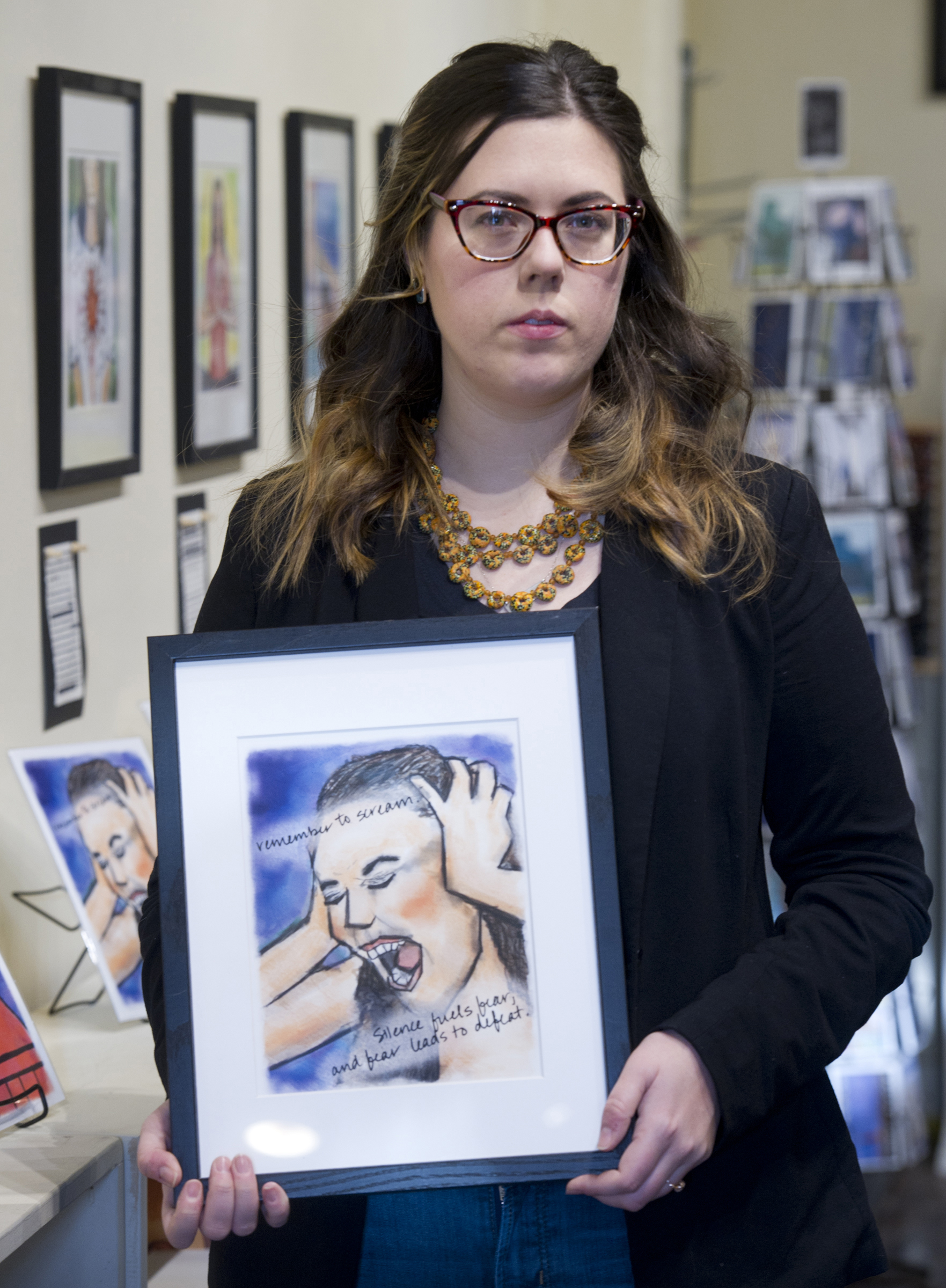 Photo by Michael Penn/Juneau Empire  Christine Carpenter holds one of her artworks in the Alaska Robotics Gallery on Jan. 6,she made after being raped in Italy.
