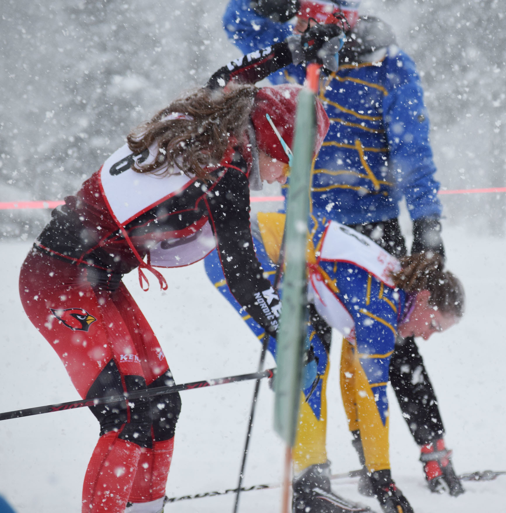 Maria Salzetti (6) of Kenai and Katie Holmes of Homer rush to change skis, from classic to skate style, Friday afternoon at the snowy Kenai Golf Course. (Photo by Joey Klecka/Peninsula Clarion)