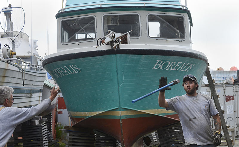 Two Pacific Star Seafoods employees work to stabilize a commercial drift fishing boat at the company's Kenai wharf.