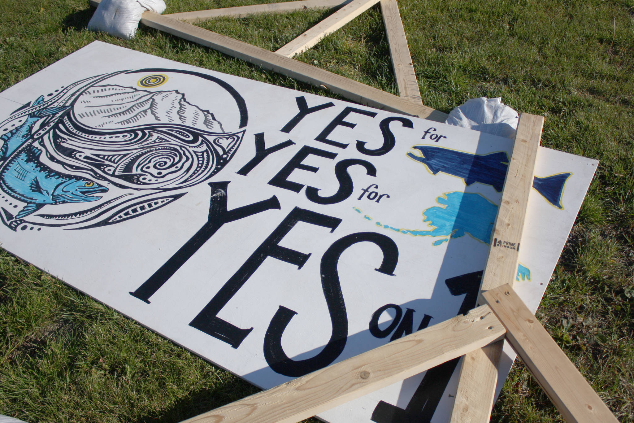 A sign supporting the Stand for Salmon ballot initiative lies on the grass near the intersection of Bridge Access Road and Kenai Spur Highway on Tuesday in Kenai. (Photo by Erin Thompson/Peninsula Clarion)