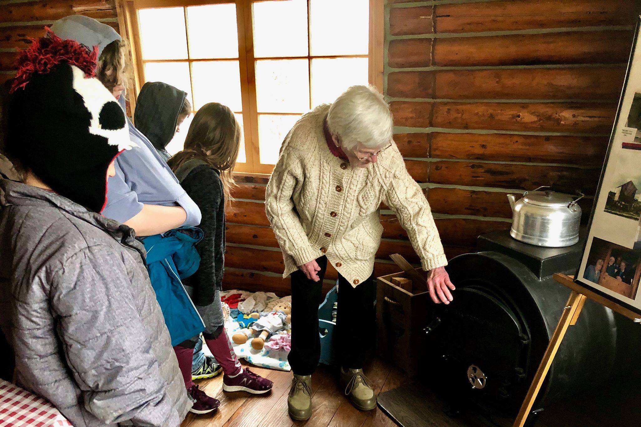 Marge Mullen shows a third-grade class how the residents of the Howard Lee Homestead heated their home, on Wednesday, Oct. 17, 2018, in Soldotna, AK. (Photo by Victoria Petersen/Peninsula Clarion)