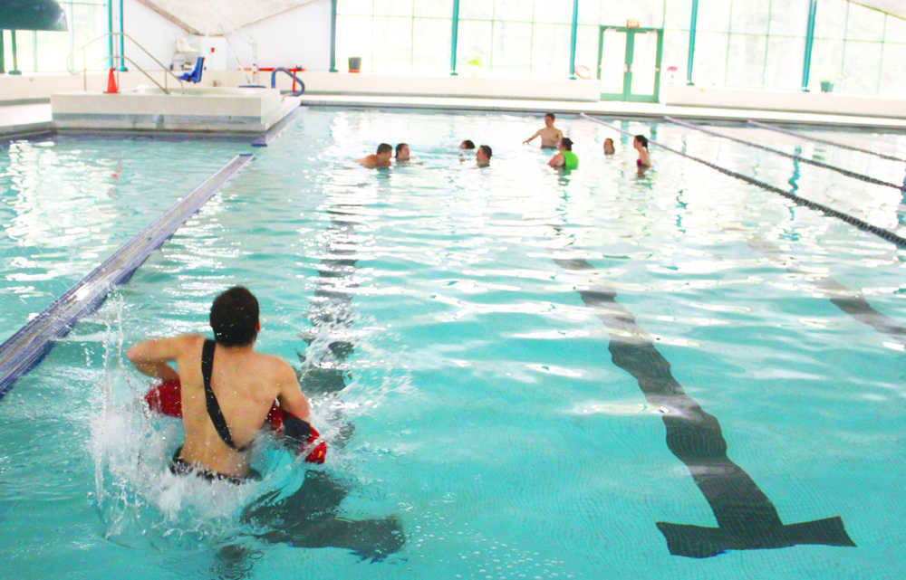 Landon Lightfoot jumps into the Nikiski pool during a training scenario, June 30, 2014, at the Nikiski Pool, in Nikiski, Alaska. (Photo by Kelly Sullivan/ Peninsula Clarion)