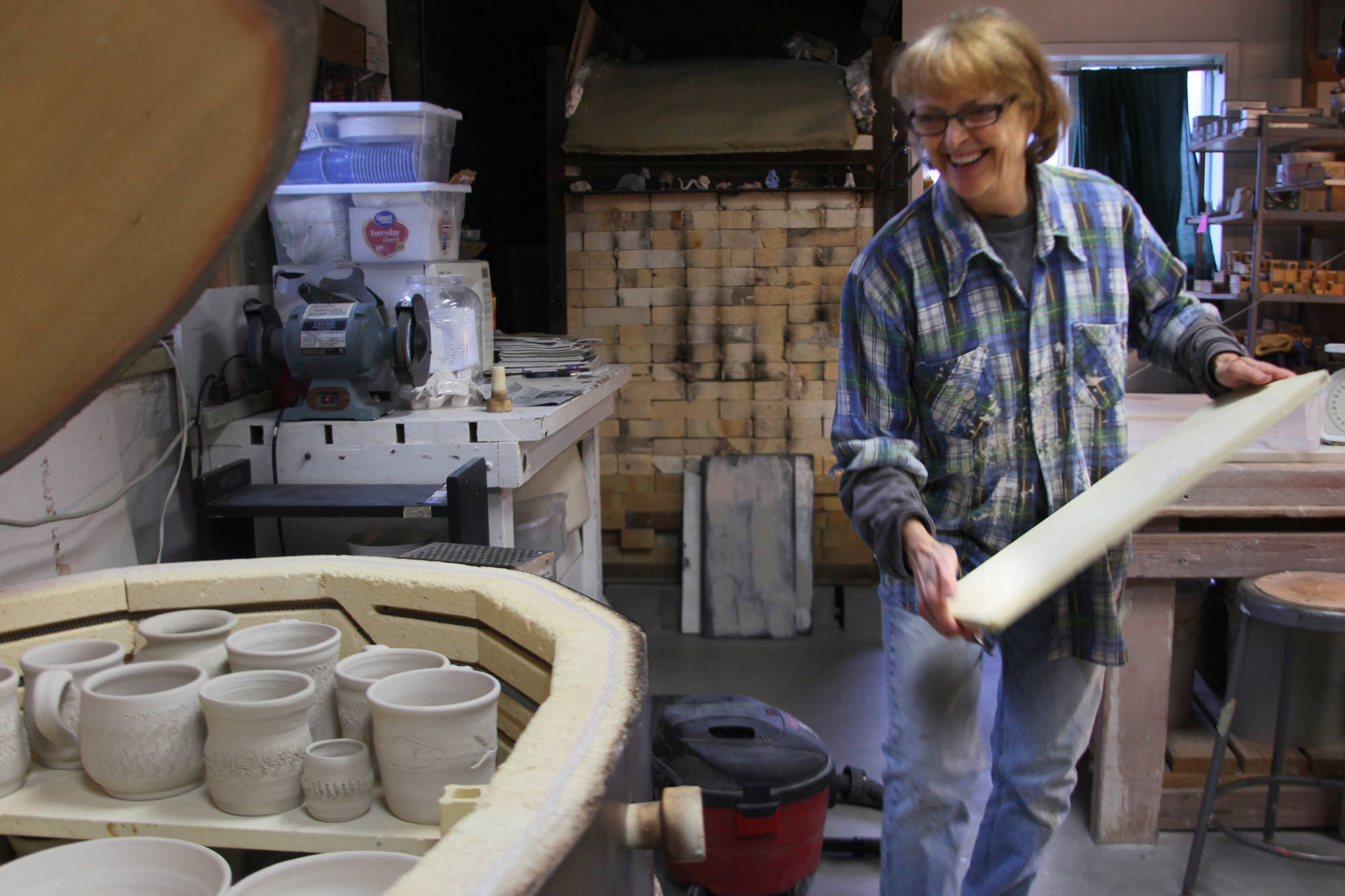 Kenai Potters Guild member Judy Brandt loads a gas-fired kiln with cups and bowls made by Guild members on Thursday, Oct. 12, 2017 at the group’s studio in Kenai. The Potters guild is preparing for a busy winter with weekly classes, a “Clay on Display” art show presently sitting in the Kenai Fine Art Center gallery, and a new kind of kiln which they’ll be experimenting with this weekend. (Ben Boettger/Peninsula Clarion)