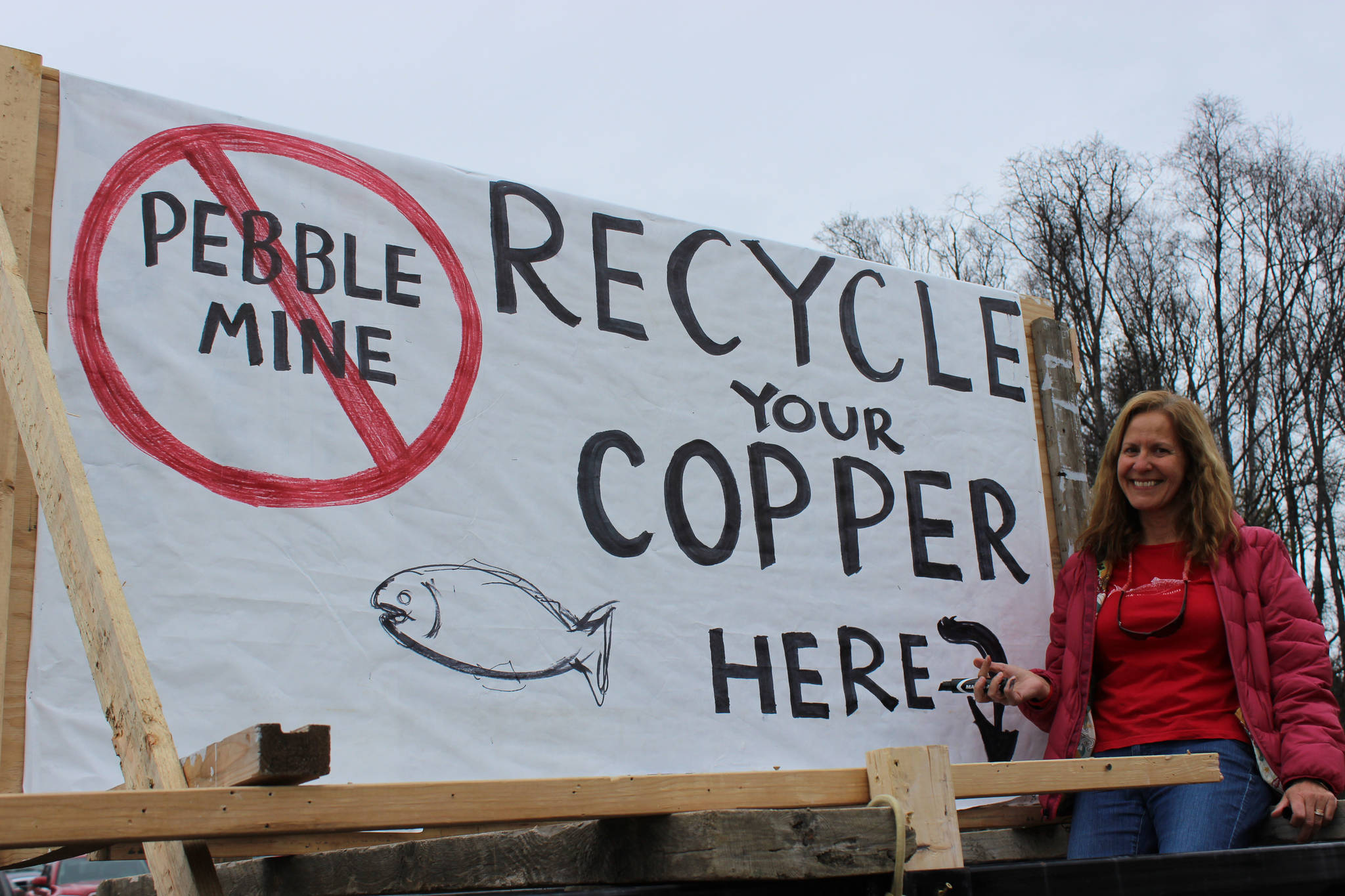 Preparing for the crowd attending the U.S. Army Corps of Engineers community scoping meeting for Pebble Limited Partnership’s proposed Pebble mine, Dan Laylord (not pictured) and Judy Gonsalves post a reminder that copper can be recycled, not just mined. PLP is proposing the open-pit copper-gold molybdenun pophyry mine for Southwest Alaska. It would be powered by Hilcorp’s natural gas from the Kenai Peninsula. The meeting was held at Homer High School, Homer, Alaska, on Wednesday, April 11, 2018. (Photo by McKibben Jackinsky)