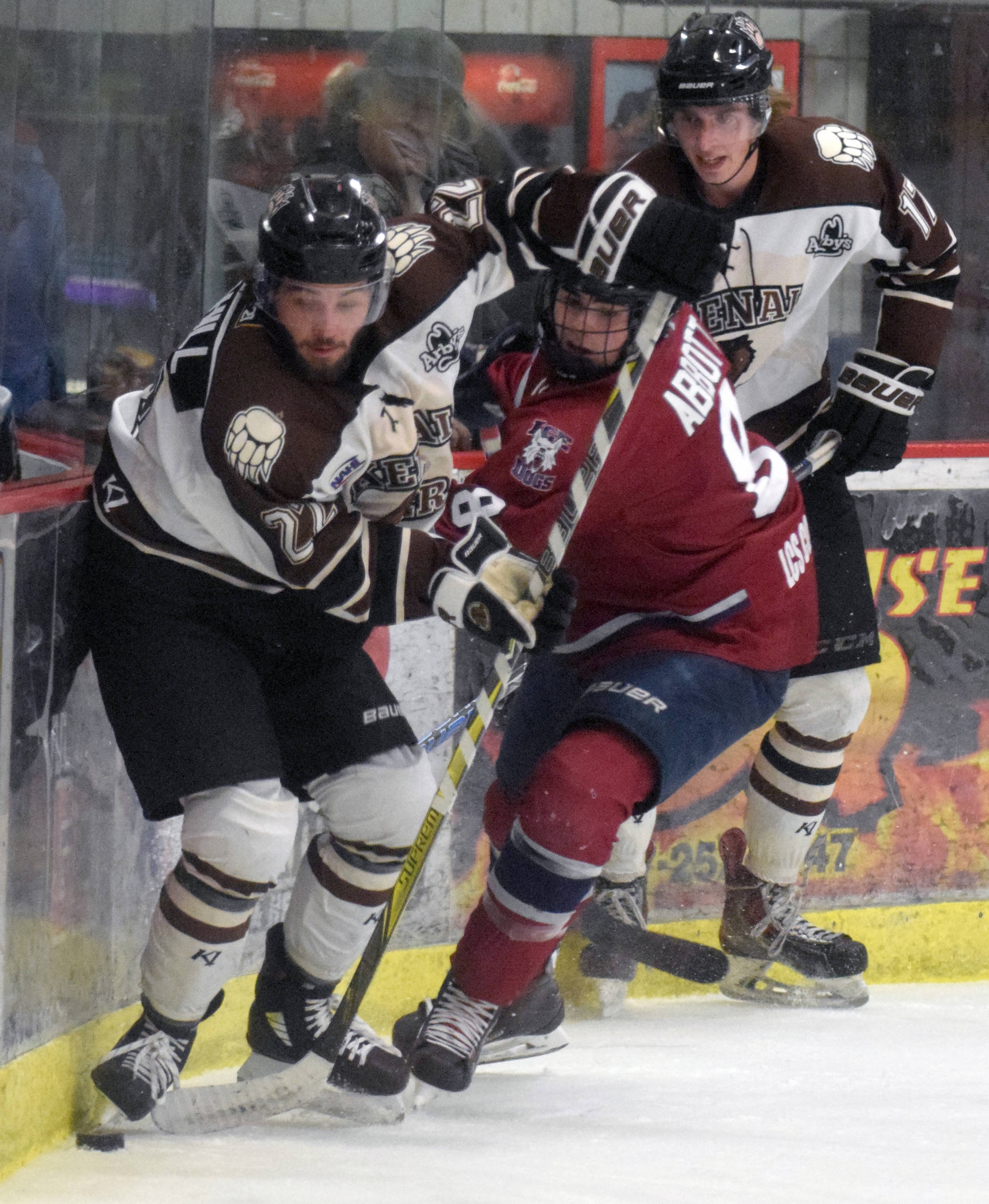 Kenai River Brown Bears defenseman Connor Scahill controls the puck in front of Dylan Abbott of the Fairbanks Ice Dogs and Sutton McDonald of the Brown Bears on Friday, Nov. 23, 2018, at the Soldotna Regional Sports Complex. (Photo by Jeff Helminiak/Peninsula Clarion)