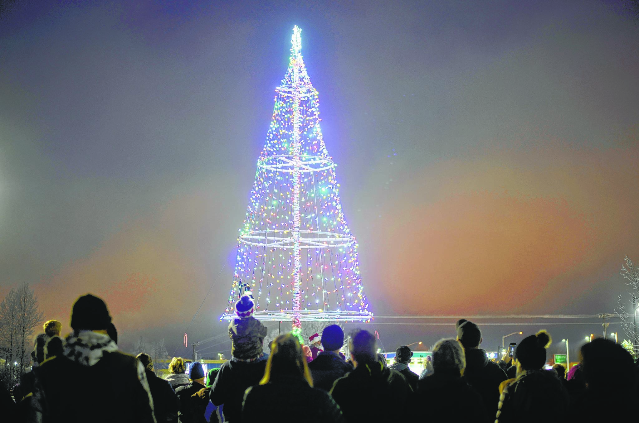 The community gathers beneath a Christmas tree during Soldotna’s tree lighting event Dec. 2, 2017, at Soldotna Creek Park. (Photo by Kat Sorensen/Peninsula Clarion)