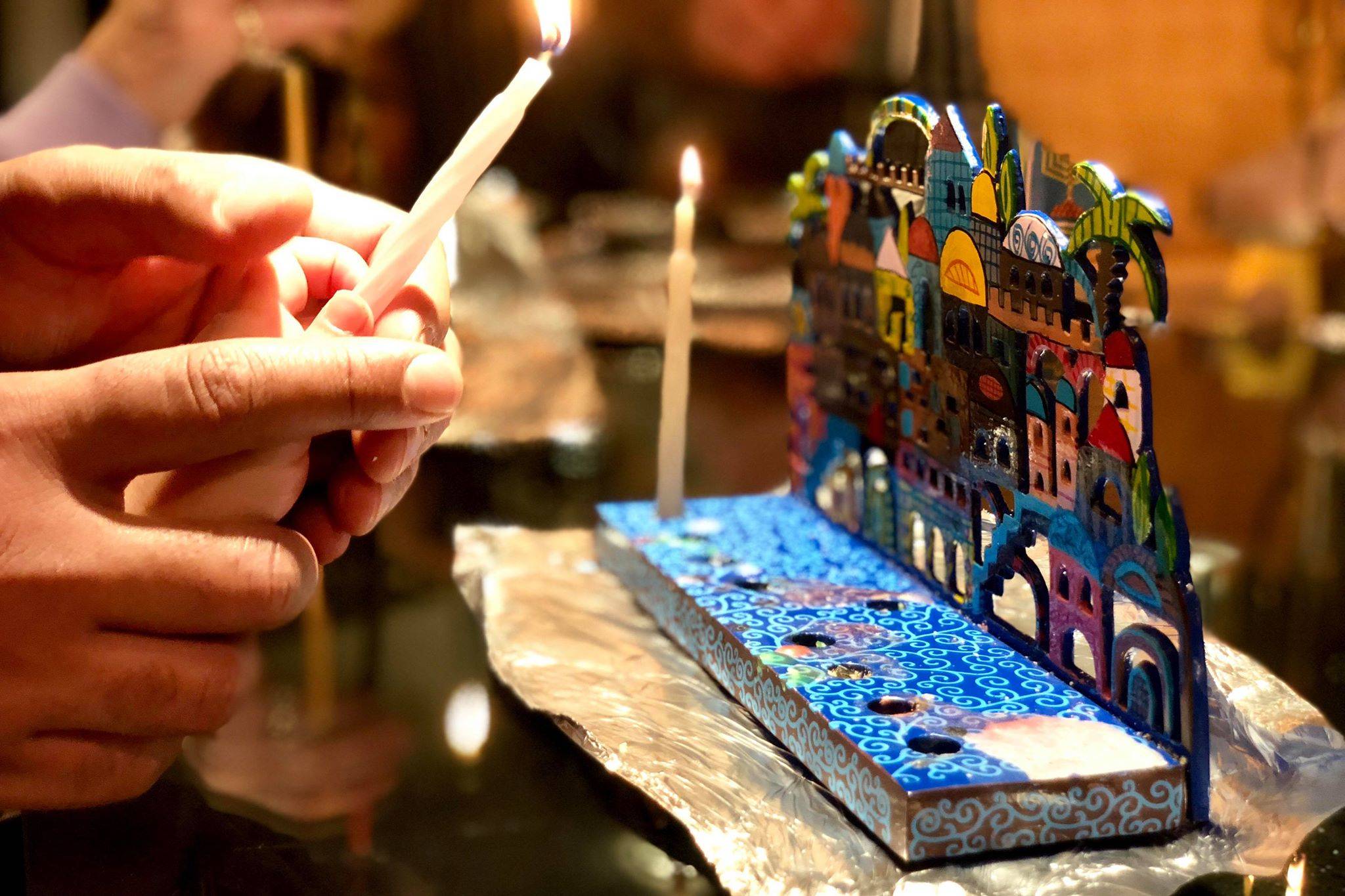 A father helps his daughter light a candle on their menorah at the Briat Elohim Jewish Congregation Hanukkah party on Dec. 1, 2018, in Kenai, Alaska. (Photo by Victoria Petersen/Peninsula Clarion)