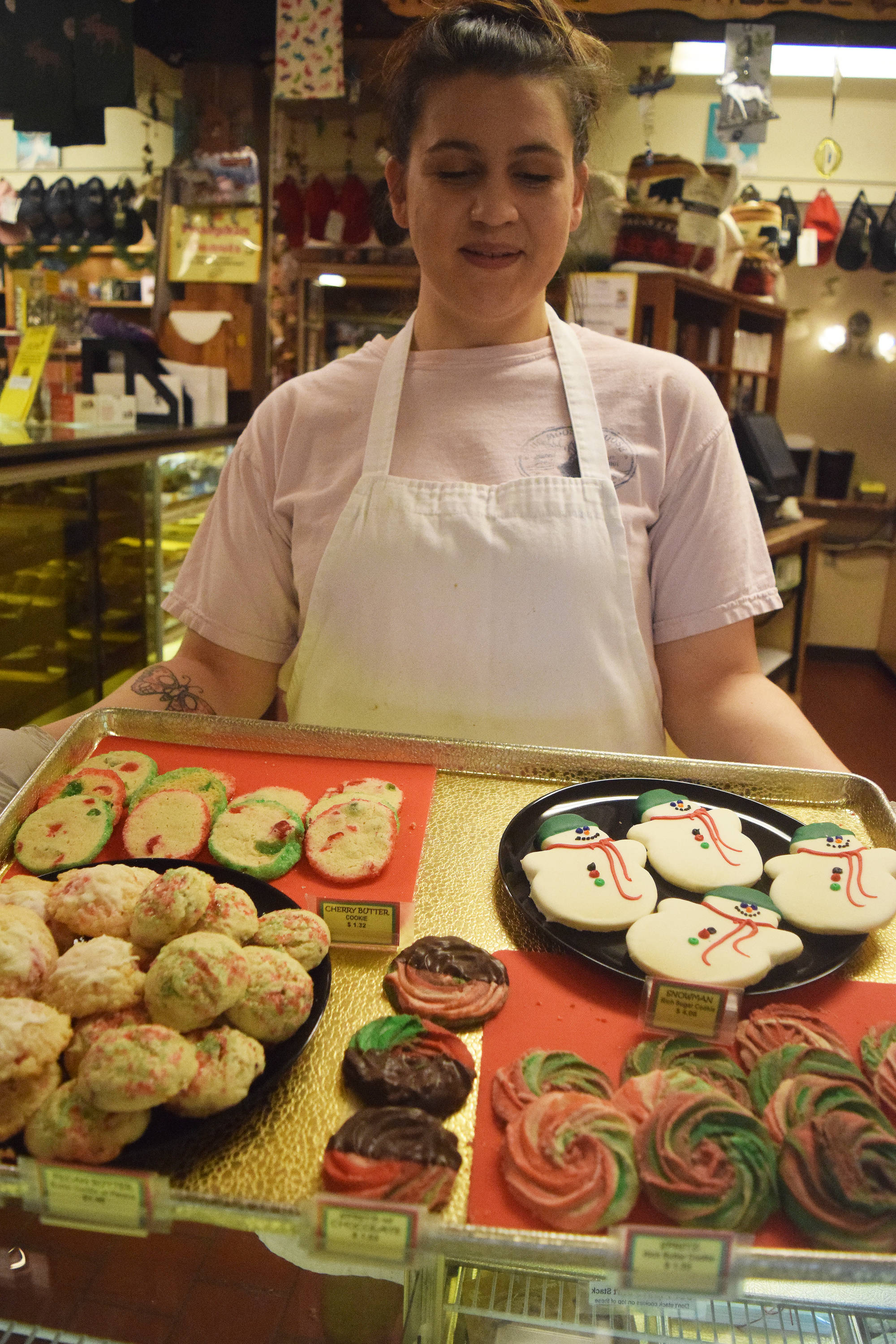 The Moose is Loose employee Elainnah Lagoutaris displays a pan of holiday-themed cookies Tuesday afternoon at the popular bakery in Soldotna. (Photo by Joey Klecka/Peninsula Clarion)