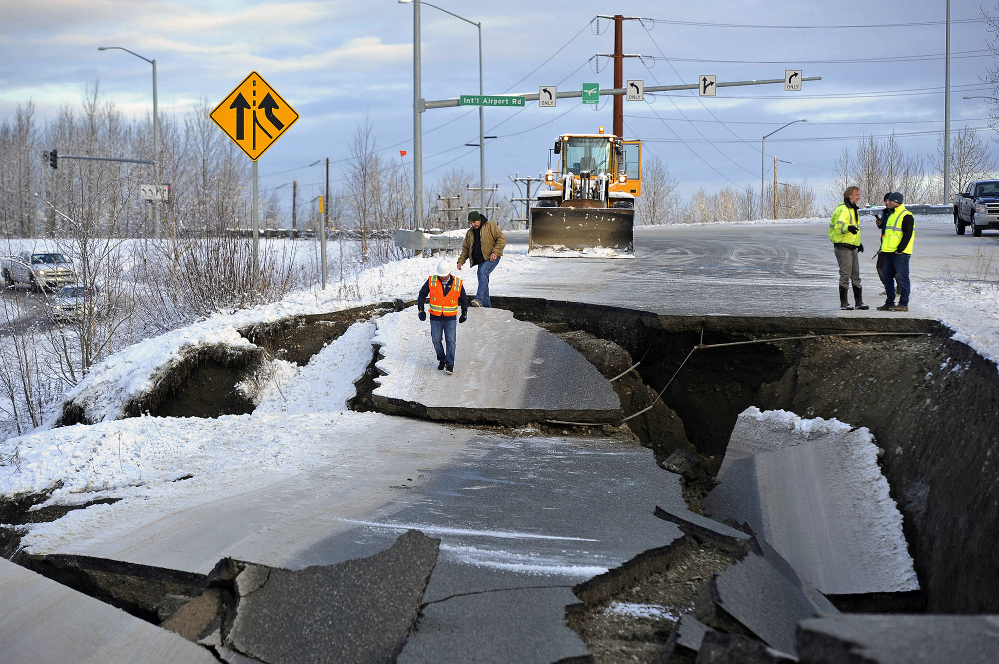 In this Friday, Nov. 30 file photo, workers inspect a road that collapsed during an earthquake in Anchorage. The off-ramp connecting Minnesota Drive and Ted Stevens Anchorage International Airport reopened Tuesday, with shoulder work completed Wednesday. (AP Photo/Mike Dinneen, File)