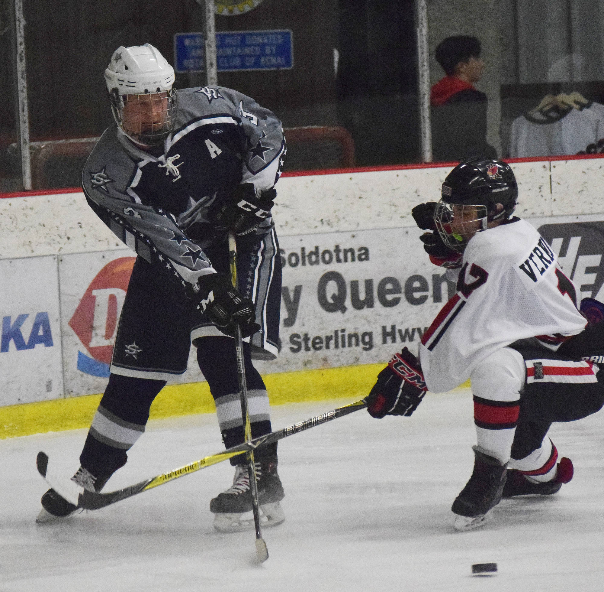 Soldotna’s Galen Brantley III keeps the puck away from Kenai Central’s Travis Verkuilen (right) Thursday evening at the Kenai Multi-Purpose Facility. (Photo by Joey Klecka/Peninsula Clarion)