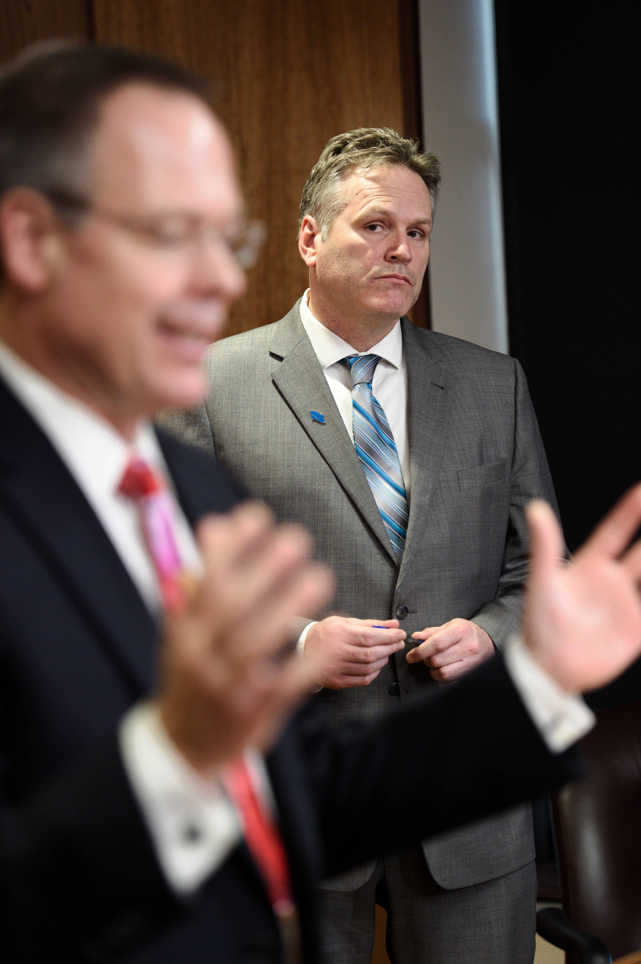 Commissioner Designee Bruce Tangeman presents bills to pay residents cut PFD funds as Gov. Mike Dunleavy watches during a press conference at the Capitol on Wednesday, Jan. 16, 2019. (Michael Penn | Juneau Empire)