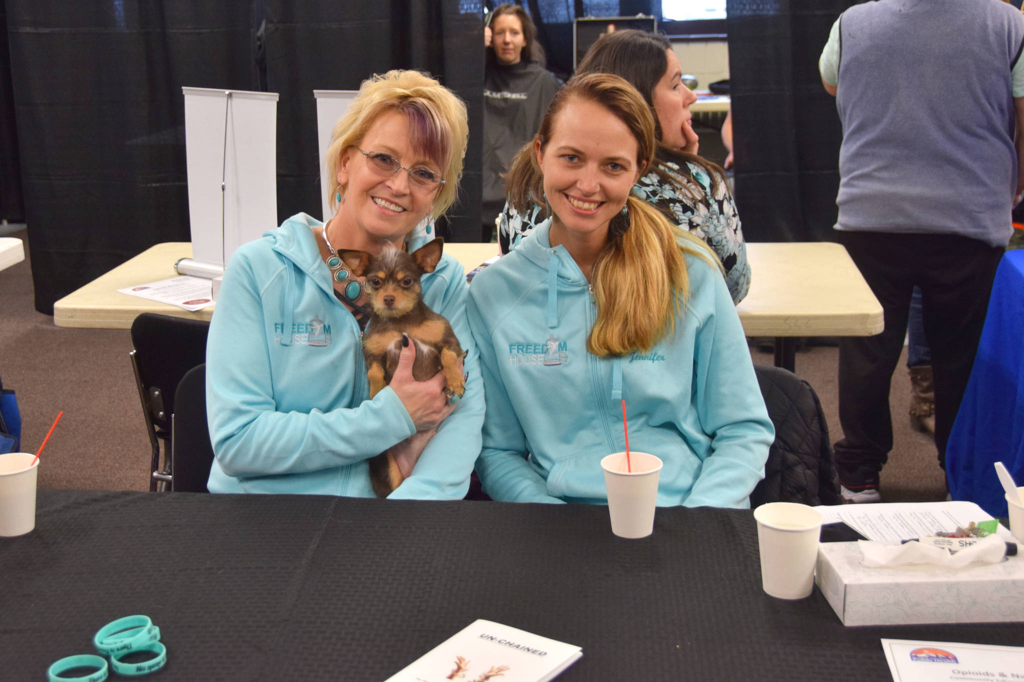 Gail Kennedy, left, Jennifer Waller, and Meiko, the therapy dog from Freedom House, offer their services during Project Homeless Connect at the Soldotna Regional Sports Complex on Wednesday, Jan. 23, 2019. (Photo by Brian Mazurek/Peninsula Clarion)