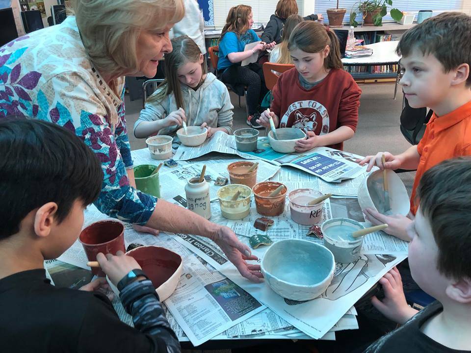 Debbie Adamson, president of the Kenai Potters Guild, assists a group of fifth-graders at Soldotna Elementary who are working on pottery projects this week for a fundraiser that will buy new playground equipment for the school on Thursday, in Soldotna. (Photo by Victoria Petersen/Peninsula Clarion)