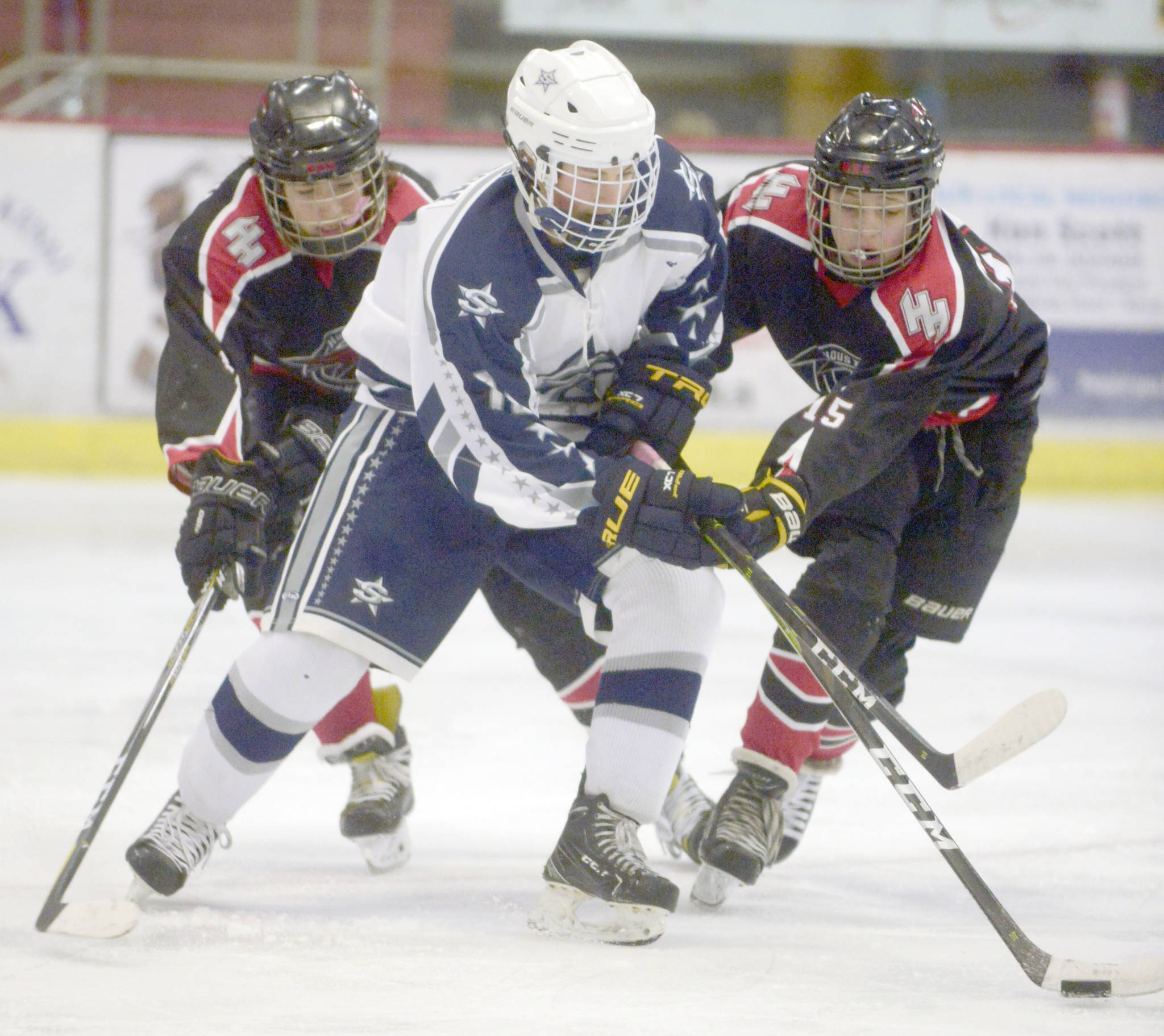 Soldotna’s Dylan Walton battles for the puck with Houston’s Isaiah Rasnake-Squires and Eric Preboski on Friday, Jan. 25, 2019, at the Soldotna Regional Sports Complex. (Photo by Jeff Helminiak/Peninsula Clarion)