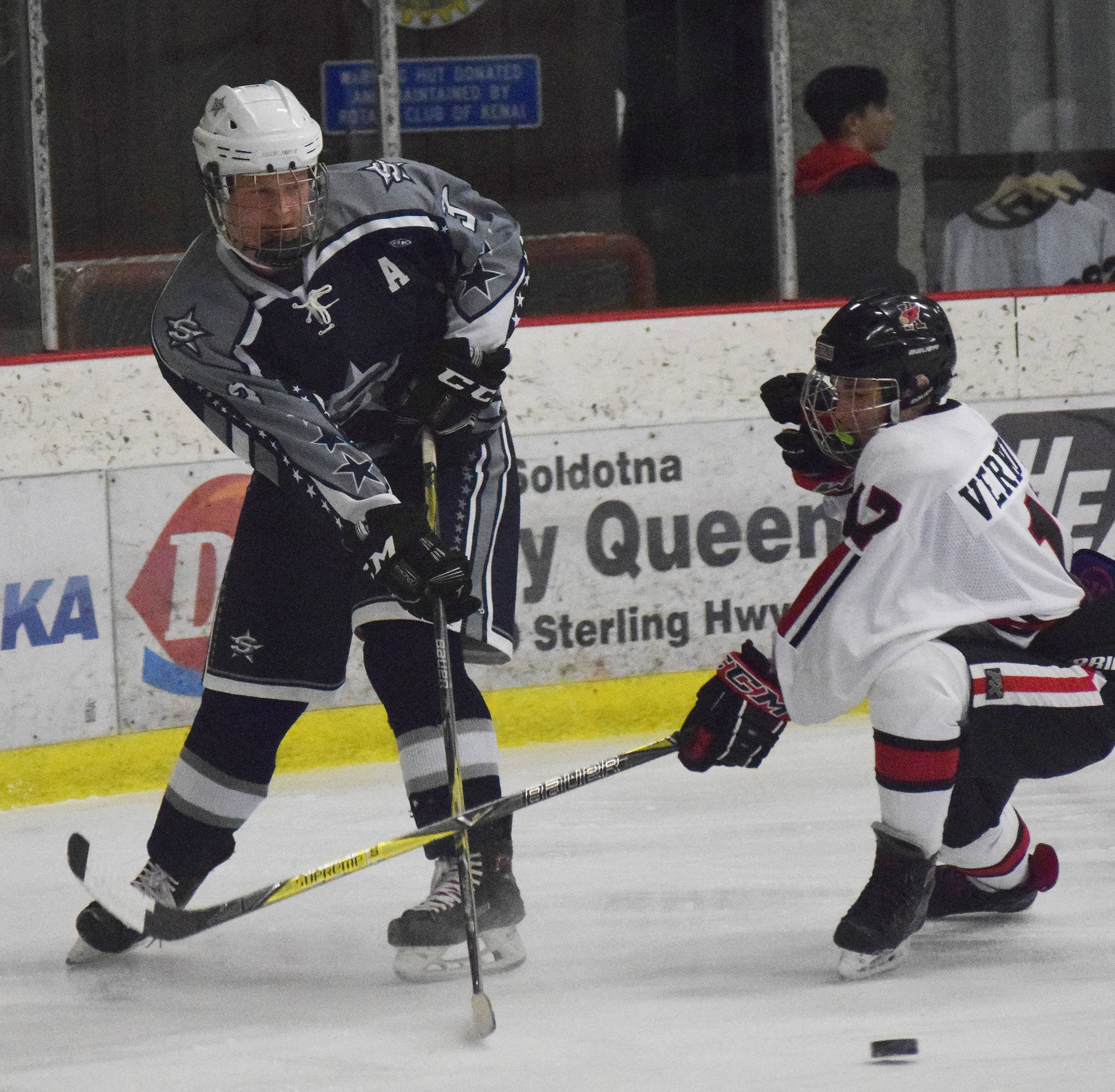 Soldotna’s Galen Brantley III keeps the puck away from Kenai Central’s Travis Verkuilen (right) Dec. 20, 2018, evening at the Kenai Multi-Purpose Facility. (Photo by Joey Klecka/Peninsula Clarion)