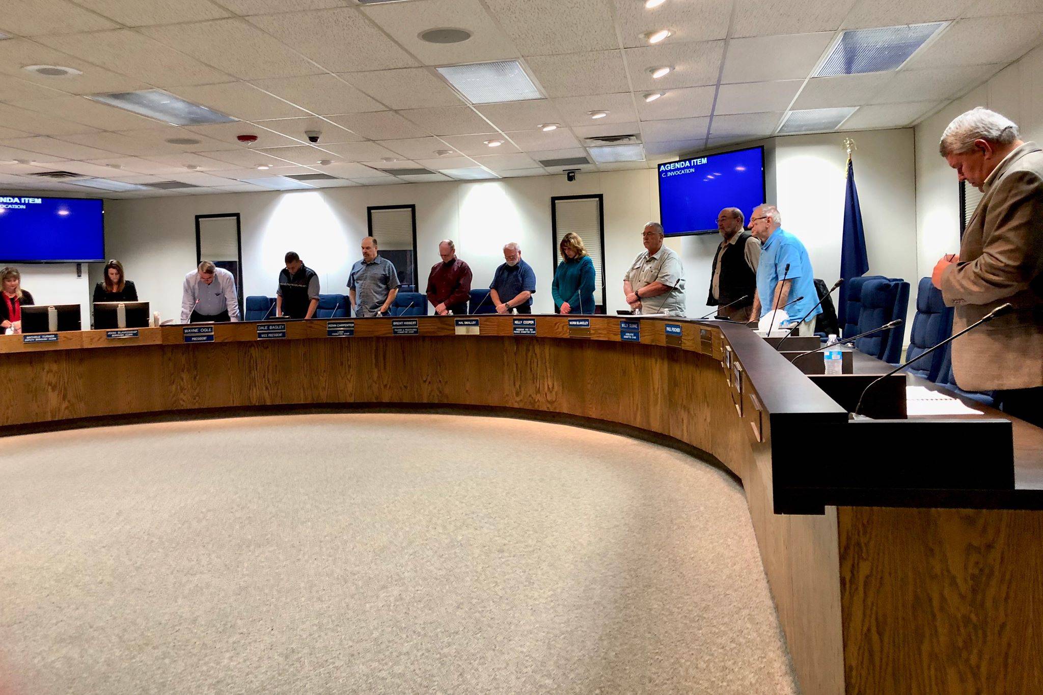 The Kenai Peninsula Borough Assembly stands in silence while Assembly President Wayne Ogle offers an invocation before the Oct. 23, 2018 meeting, in Soldotna. (Photo by Victoria Petersen/Peninsula Clarion)