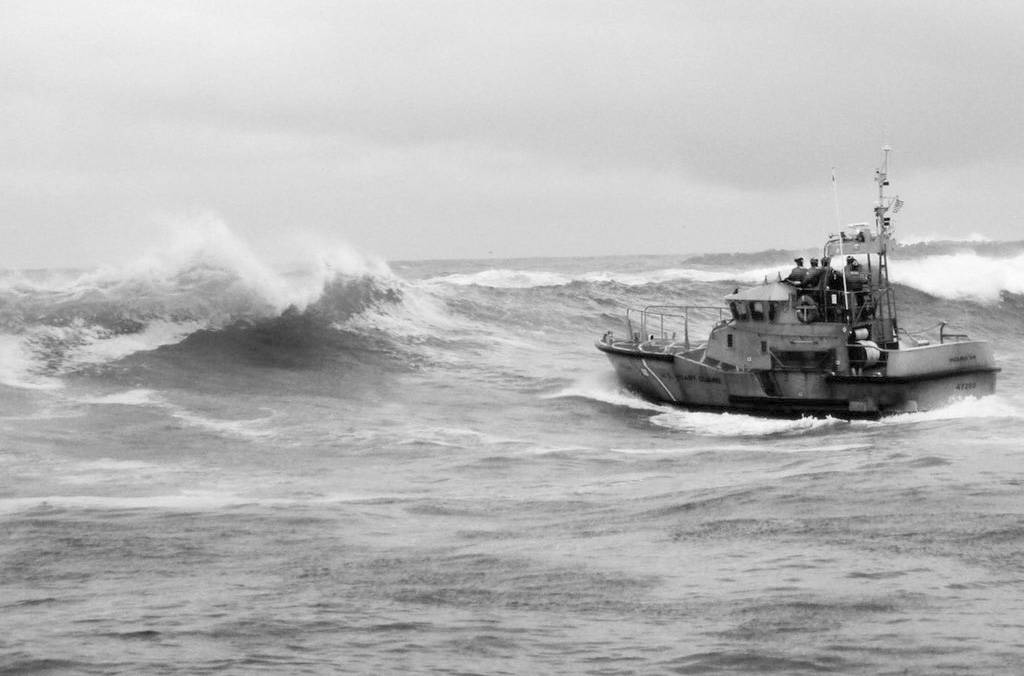 In this Tuesday, Jan. 8, 2019 photo, provided by the U.S. Coast Guard, a U.S. Coast Guard boat crew responds to three fishermen in the water after the commercial fishing vessel Mary B II capsized while crossing Yaquina Bay Bar off the coast of Newport, Ore. (U.S. Coast Guard via AP)