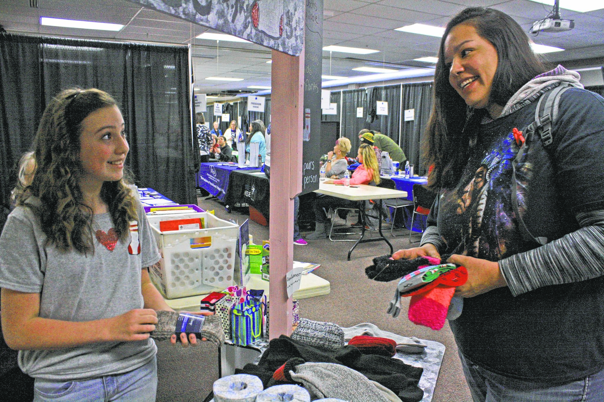 Aleea Faulkner, 12, shares socks with mom Wausaumoutouikwe Sandman-Shelifoe on Wednesday, Jan. 24, 2018, during Project Homeless Connect at the Soldotna Sports Complex. Faulkner spearheaded a sock drive to support the annual community service event. (Photo by Erin Thompson/Peninsula Clarion)