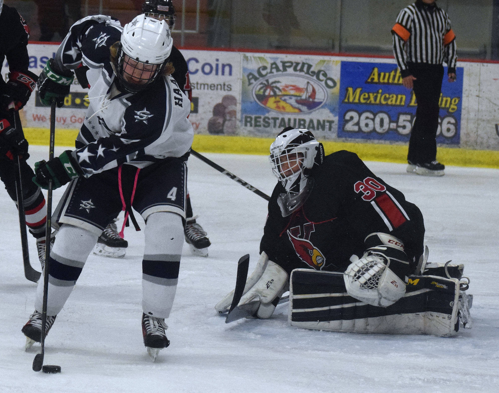 Kenai Central goaltender Jackson Cross watches as Soldotna’s Gavin Haakenson (left) works a shot attempt Wednesday night in a conference game at the Soldotna Regional Sports Complex. (Photo by Joey Klecka/Peninsula Clarion)