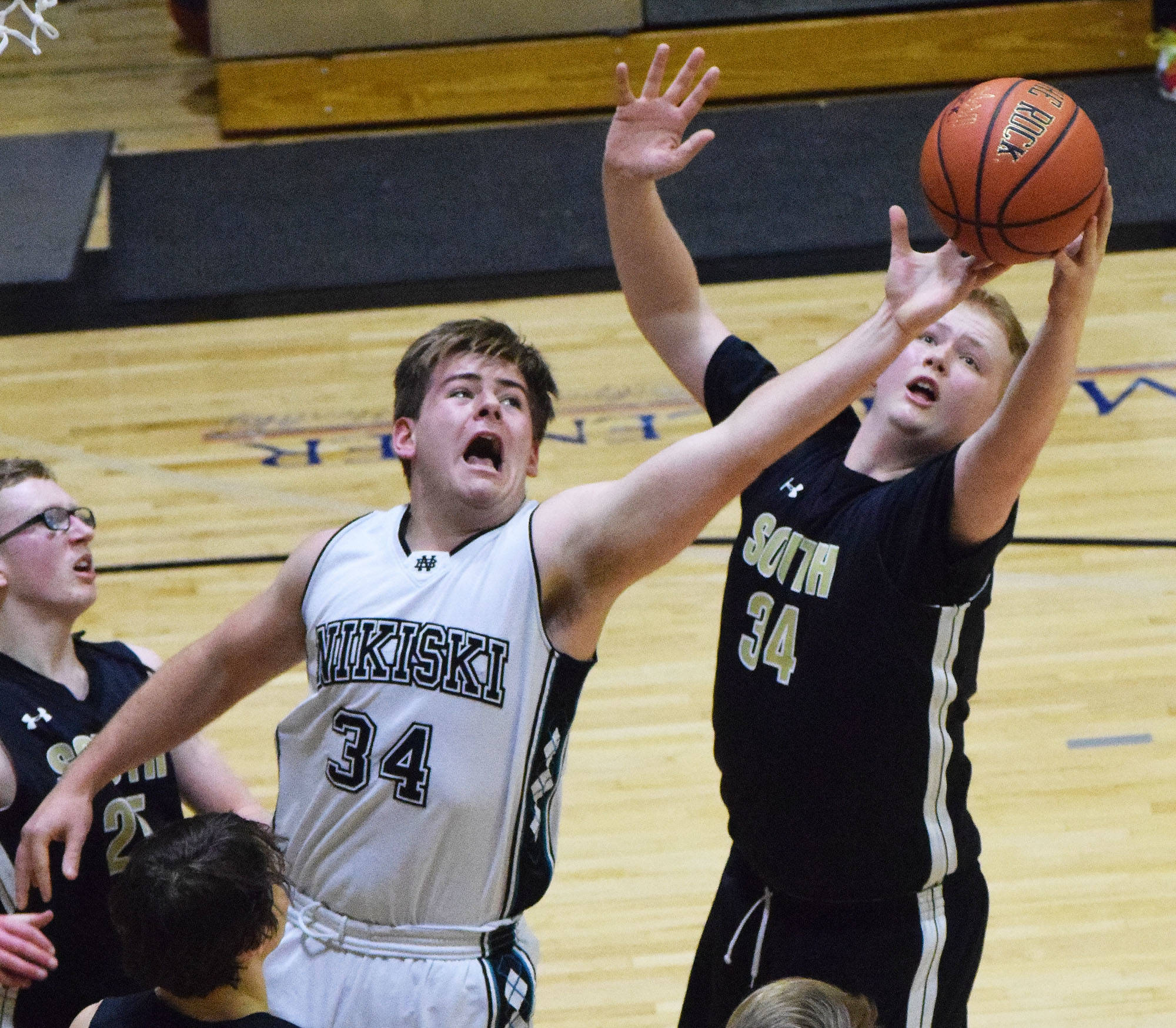 Nikiski’s Seth DeSiena (34) attempts to swipe a rebound from South’s Harry Whited Saturday at the Rus Hitchcock Nikiski Tip Off tournament. (Photo by Joey Klecka/Peninsula Clarion)