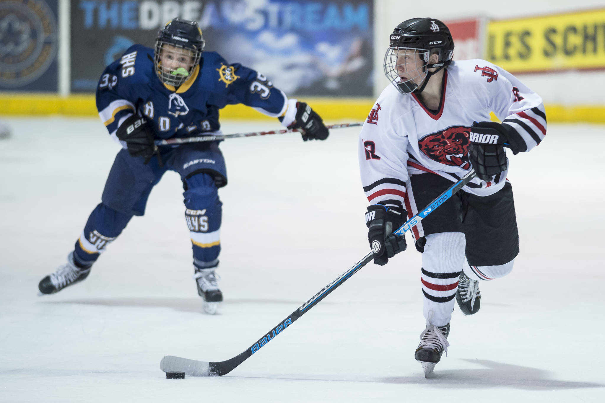 Juneau-Douglas’ Kyler Alderfer, right, moves the puck in front of Homer’s Casey Otis at Treadwell Arena on Friday, Jan. 18, 2019. JDHS won 4-3 in overtime. (Michael Penn | Juneau Empire)