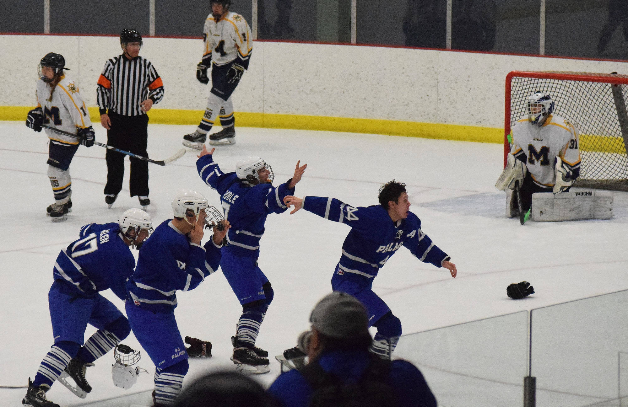 Members of the Palmer hockey team rush the ice in celebration Saturday night after defeating Homer 6-5 in overtime at the Curtis Menard Sports Complex in Wasilla. (Photo by Joey Klecka/Peninsula Clarion)