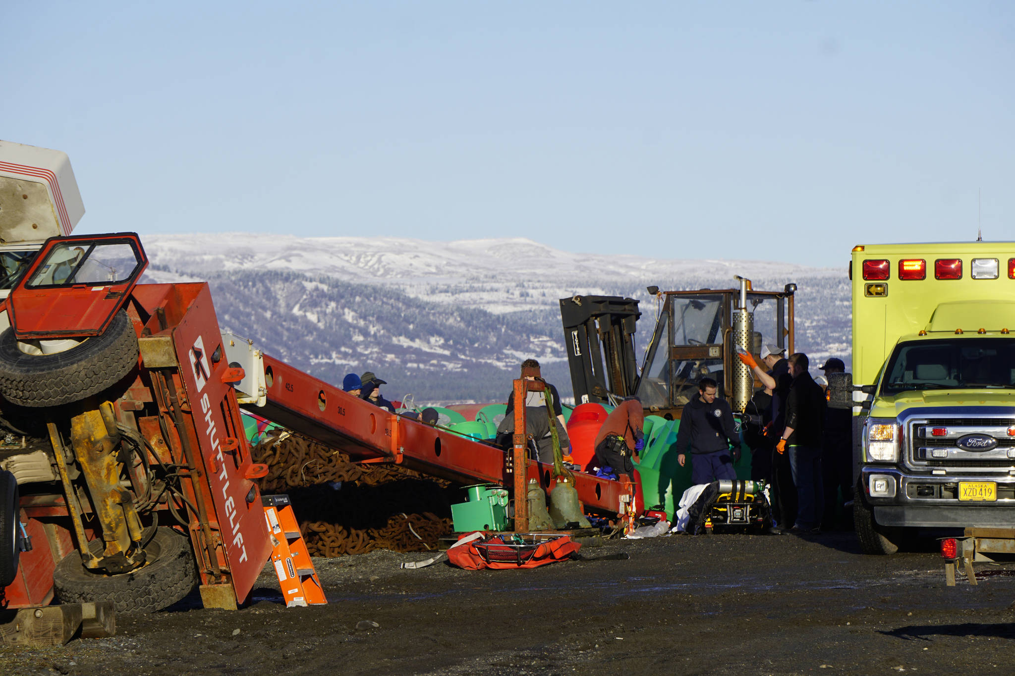 Homer Volunteer Fire Department emergency medical technicians treat a U.S. Coast Guard crew member injured when a crane tipped over at the Pioneer Dock on the Homer Spit on Thursday, Jan. 31, 2019, in Homer, Alaska. The man was later pronounced dead. (Photo by Michael Armstrong/Homer News.)