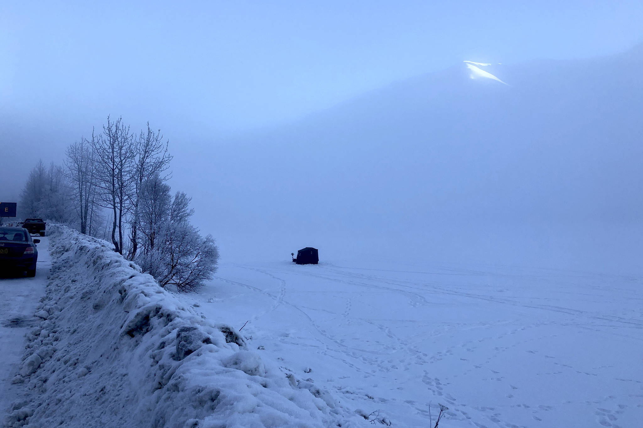 Along the Sterling Highway, people pitch a small shack on a frozen lake to go ice fishing near Cooper Landing, Alaska, on Saturday, Jan. 19, 2019. (Photo by Victoria Petersen/Peninsula Clarion)