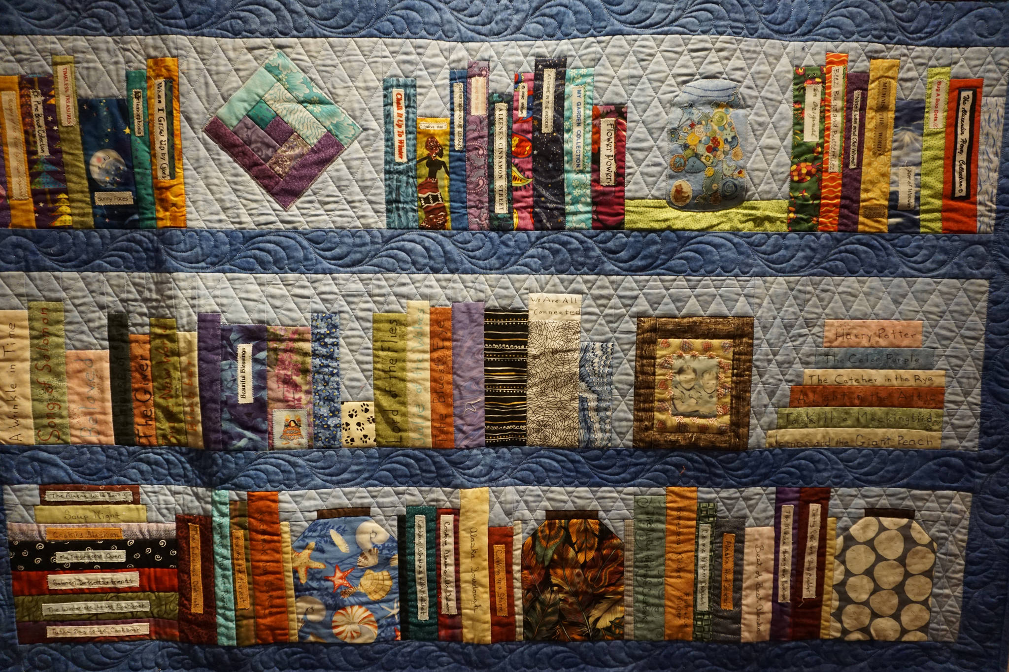 A close-up of Ruby Nofziger’s “On a Bookshelf” quilt, one of the works in the “9 Women / 9 Quilts” show that opened last Friday, Feb. 1, 2019, at the Homer Council on the Arts, in Homer, Alaska. Each panel or row of books was done by a different quilter. (Photo by Michael Armstrong/Homer News)