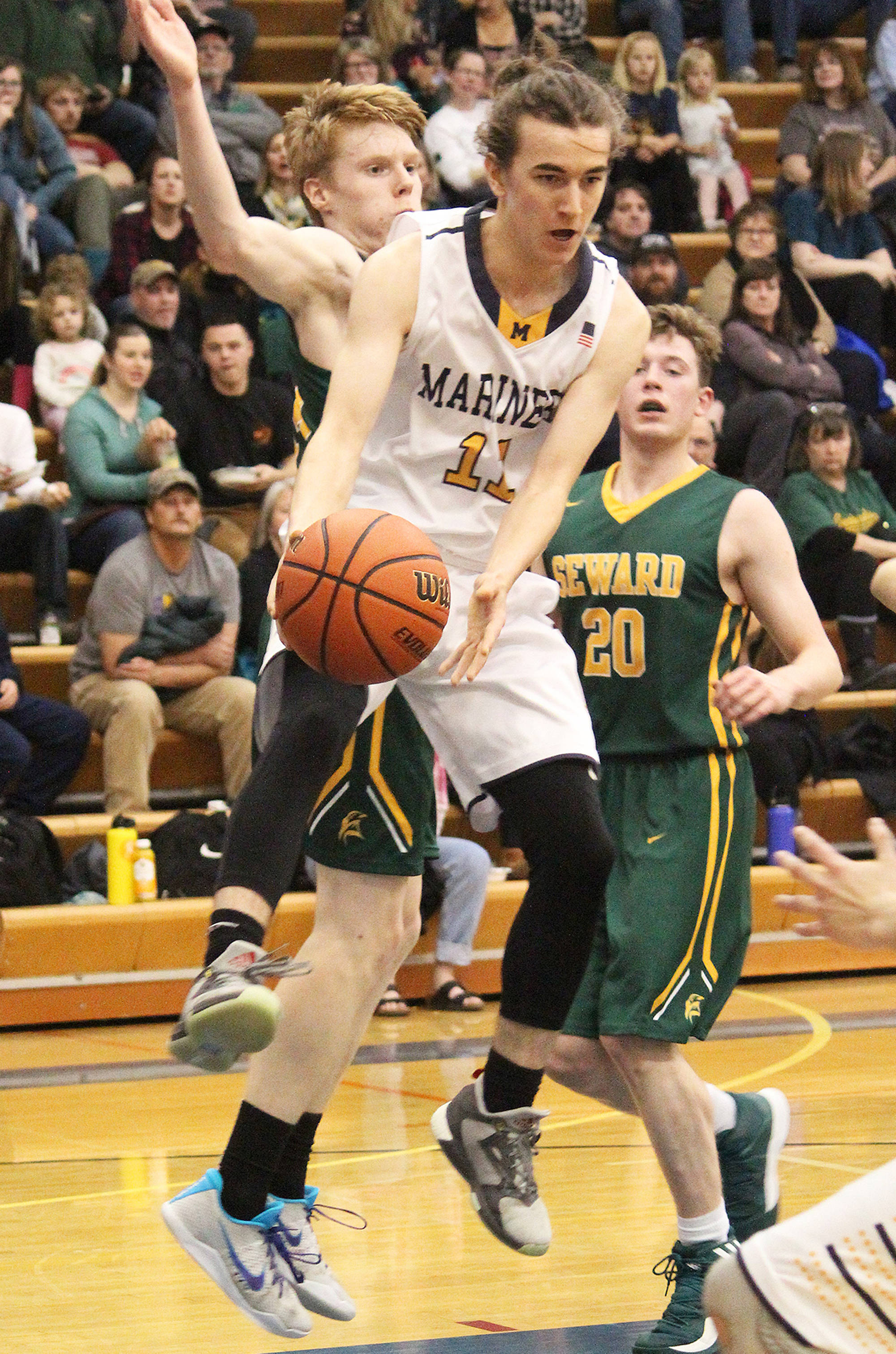 Homer’s Daniel Reutov sends the ball to a teammate under pressure from Seward players Friday, Feb. 8, 2019 during the Winter Carnival Basketball Tournament in Homer, Alaska. (Photo by Megan Pacer/Homer News)