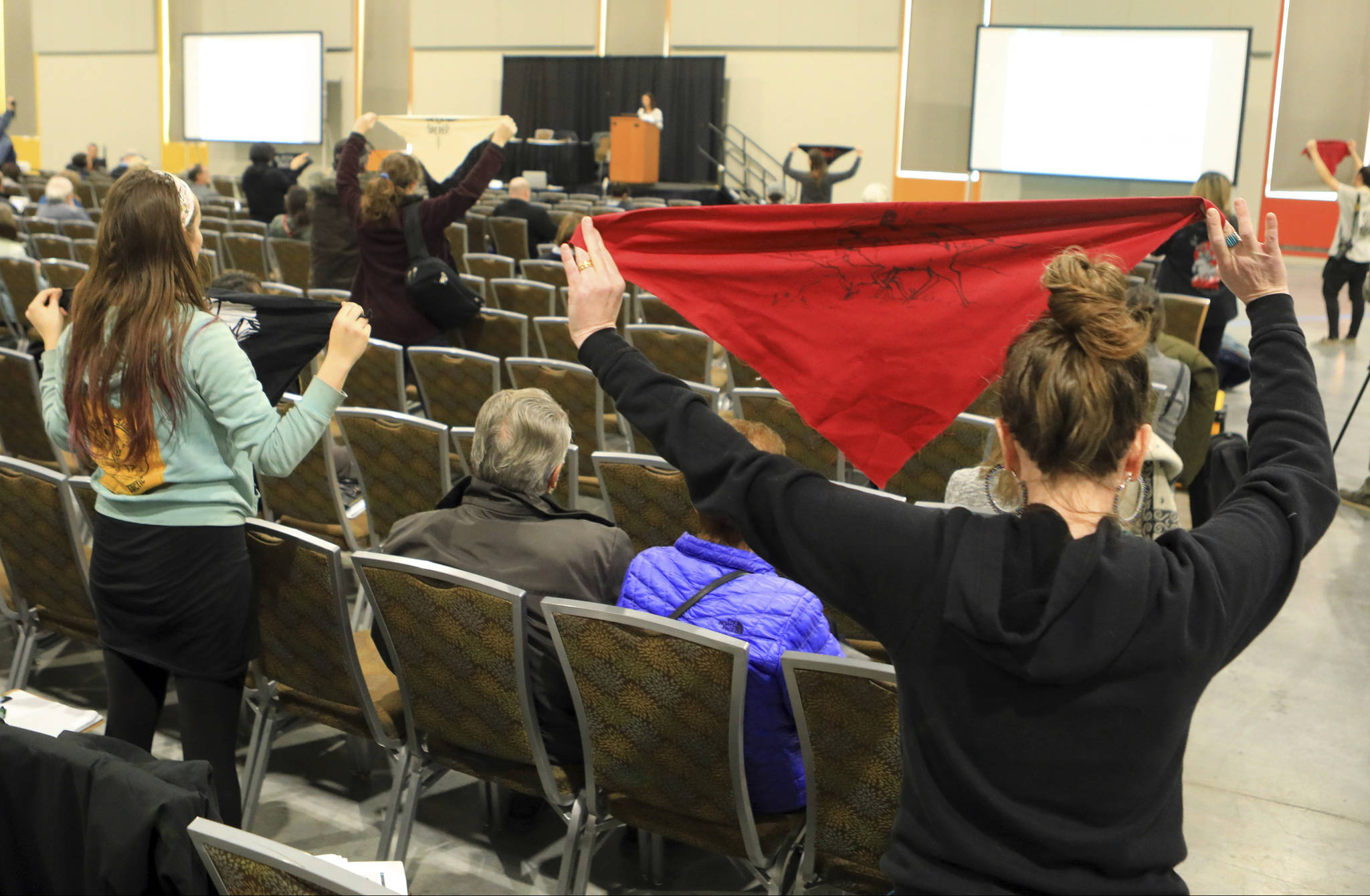 Protesters hold up flags during a public hearing on a draft environmental plan on proposed petroleum leasing within Alaska’s Arctic National Wildlife Refuge on Monday, in Anchorage. Congress in December 2017 approved a tax bill that requires oil and gas lease sales in the refuge to raise revenue for a tax cut backed by President Donald Trump. (AP Photo/Dan Joling)