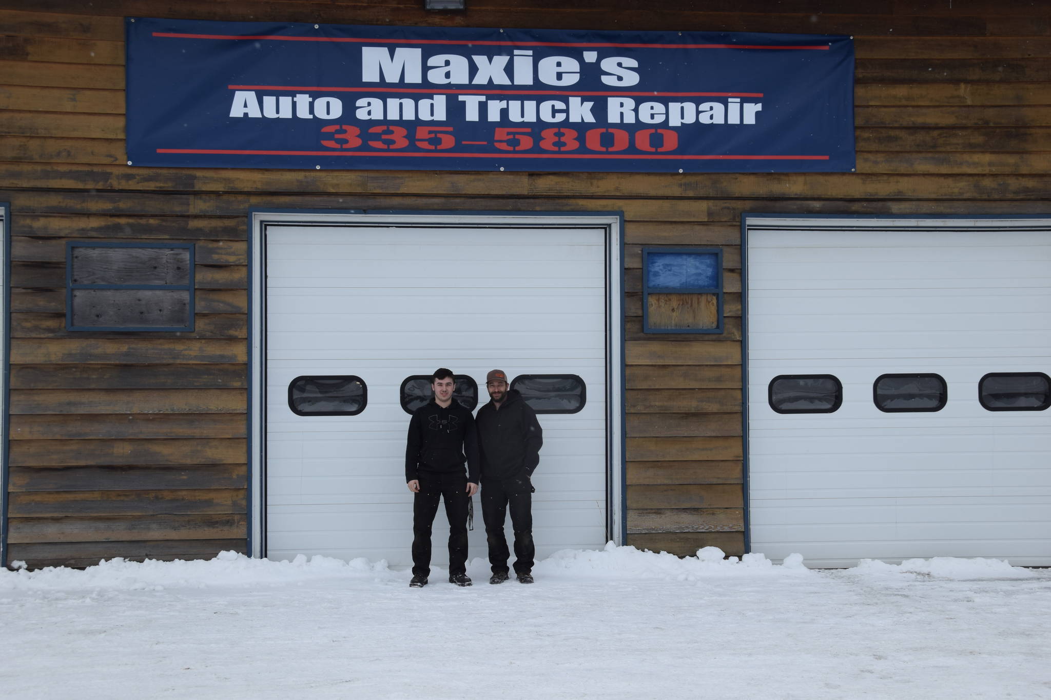 Kris Maxie, right, and his son Cameron, left, stand outside their auto repair shop in Kenai, Alaska on Feb. 20, 2019. (Photo by Brian Mazurek/Peninsula Clarion)