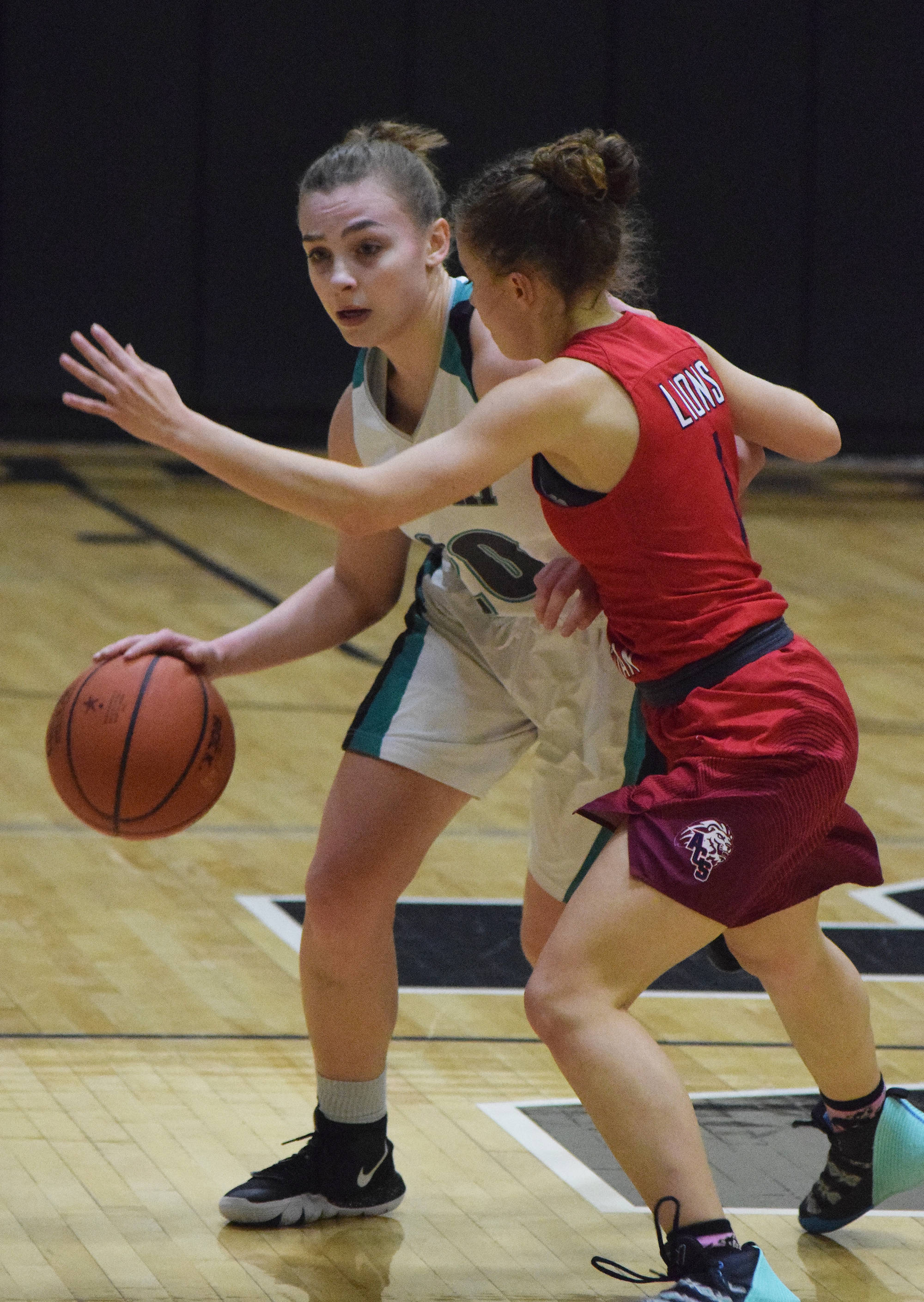 Nikiski’s Bethany Carstens (left) drives against Anchorage’s Mary Kate Parks Friday in a Southcentral Conference contest at Nikiski High School. (Photo by Joey Klecka/Peninsula Clarion)