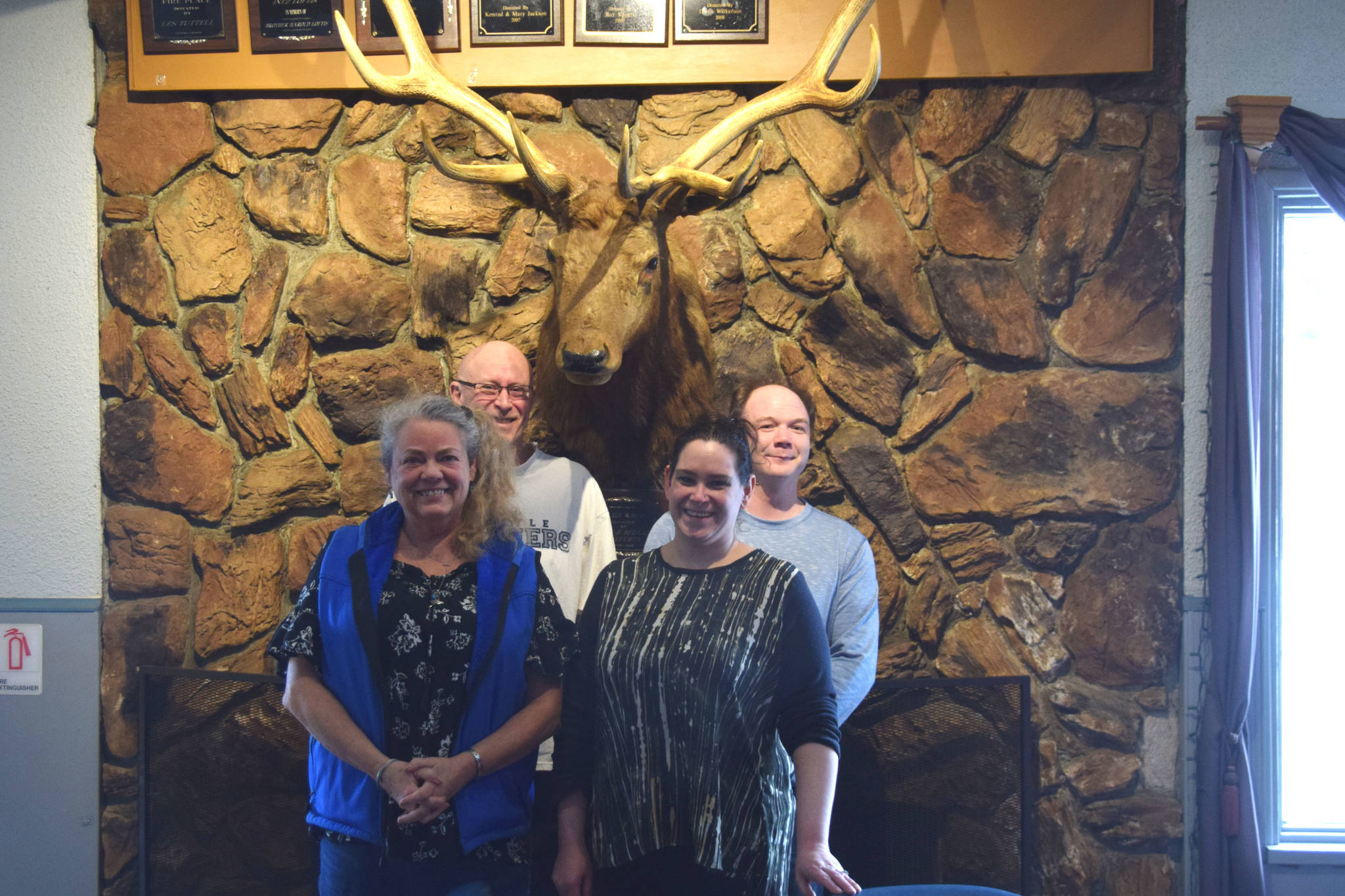 Kenai Elks Lodge members (from left to right) Mary Jackson, Ken Cole, Trina Sanford and Ryan Huss-Green stand in front of the lodge’s signature mounted elk on Tuesday. (Photo by Brian Mazurek/Peninsula Clarion)