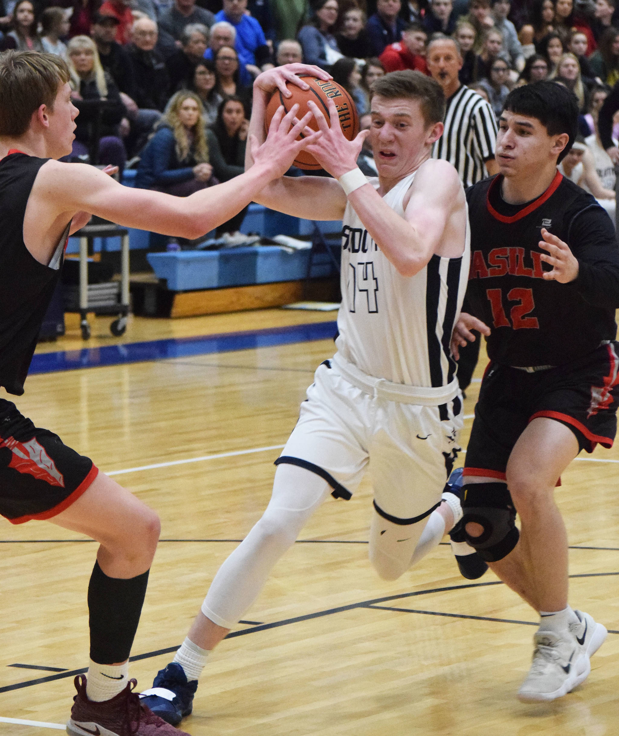Soldotna’s Ray Chumley (14) drives the lane against Wasilla defenders Andrew Devine (left) and Spencer Koval Friday night in the Northern Lights Conference semifinals at Soldotna High School. (Photo by Joey Klecka/Peninsula Clarion)