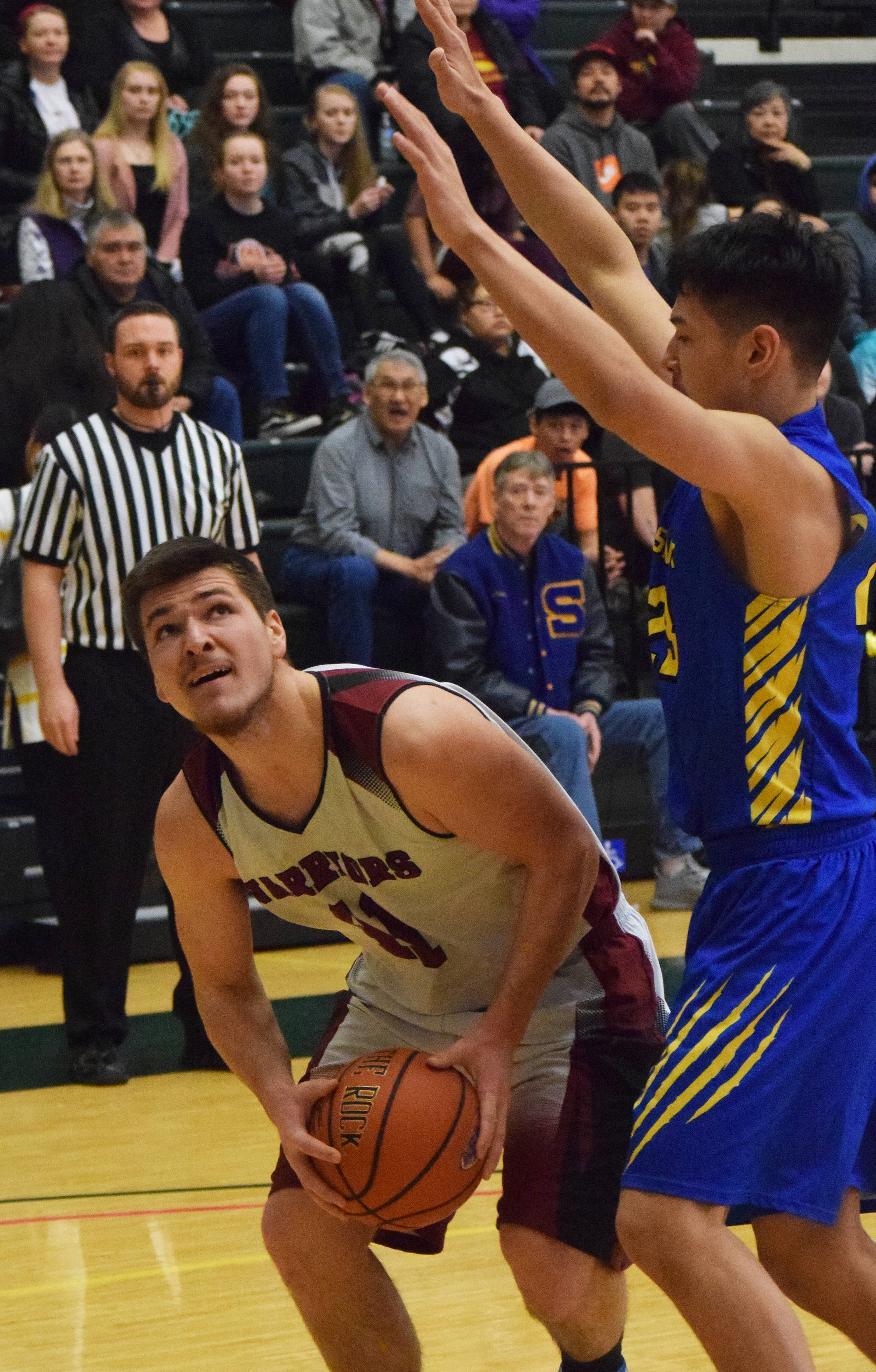 Nikolaevsk’s Michael Trail (left) attempts a shot under Savoonga’s Derek Seppilu Friday at the Class 1A state tournament at the Alaska Airlines Center in Anchorage. (Photo by Joey Klecka/Peninsula Clarion)