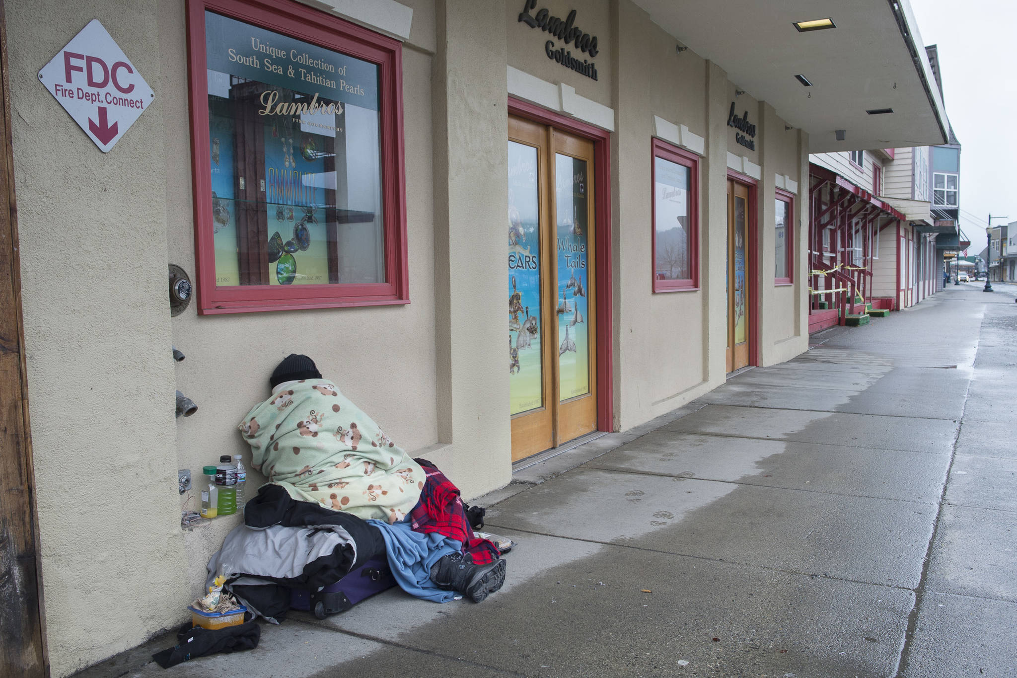 A homeless person sleeps on the sidewalk along South Franklin Street on Friday, March 15, 2019. (Michael Penn | Juneau Empire)